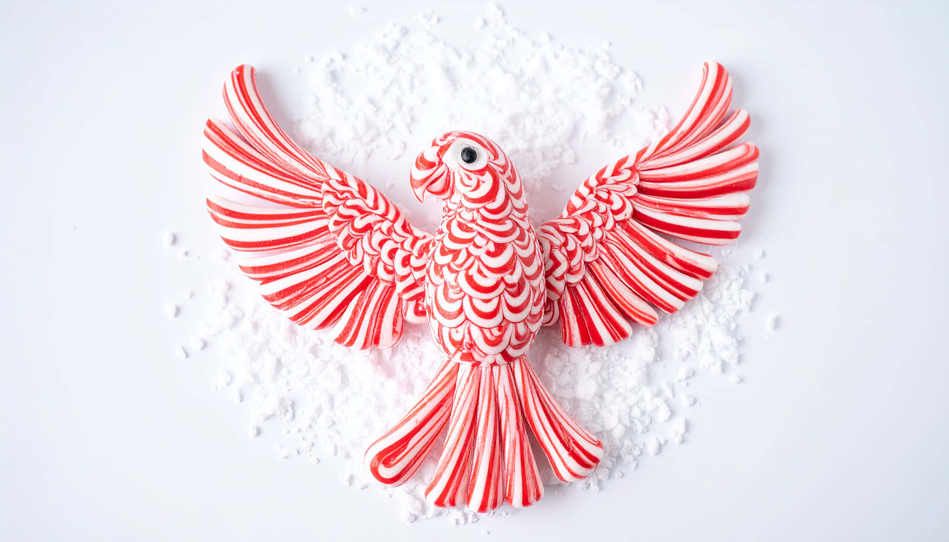 PEPPERMINT SWIRL CANDY 壁紙 — 一隻紅白條紋糖果鸚鵡展開翅膀，躺在白色糖粉床上，背景為純白色。