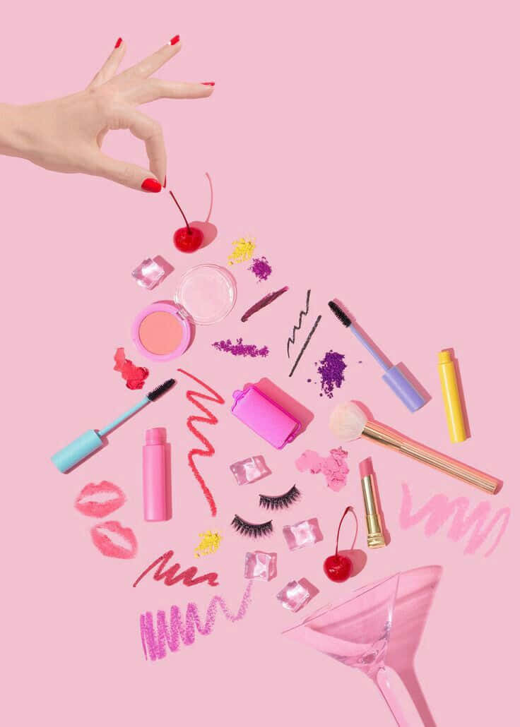 Cosmetic 桌布 壁紙 — 一隻紅色指甲的手懸浮在散落於柔和粉紅色背景上的色彩繽紛化妝品和美容產品上方。