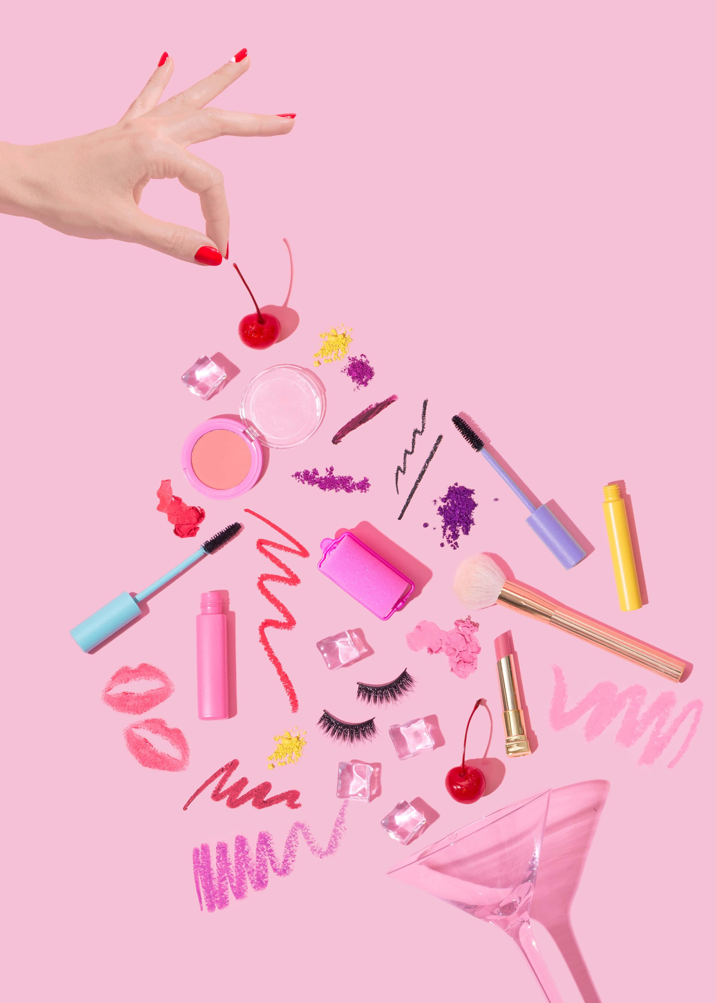 Cute Makeup 桌布 壁紙 — 一隻紅色指甲的手懸浮在散落的化妝品和櫻桃上方，背景為柔和粉紅色。