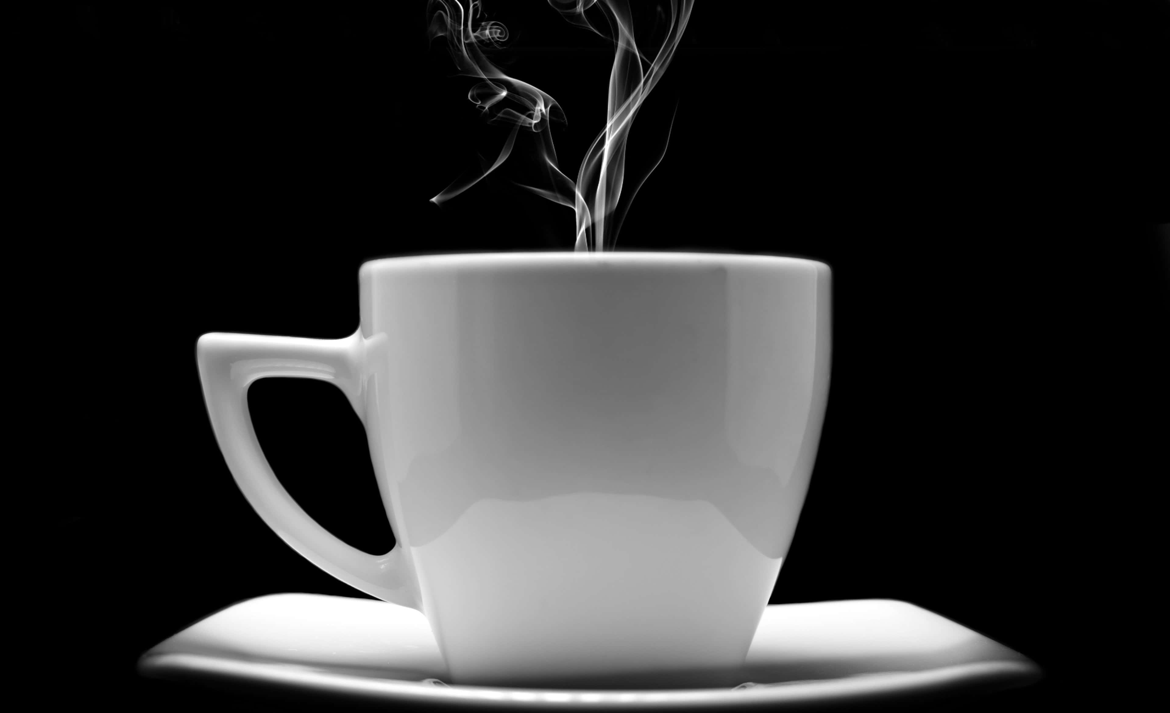 Black Coffee 桌布 壁紙 — 一隻純白色的咖啡杯放在碟子上，在純黑背景前散發出縷縷蒸氣，呈現高對比度的單色效果。