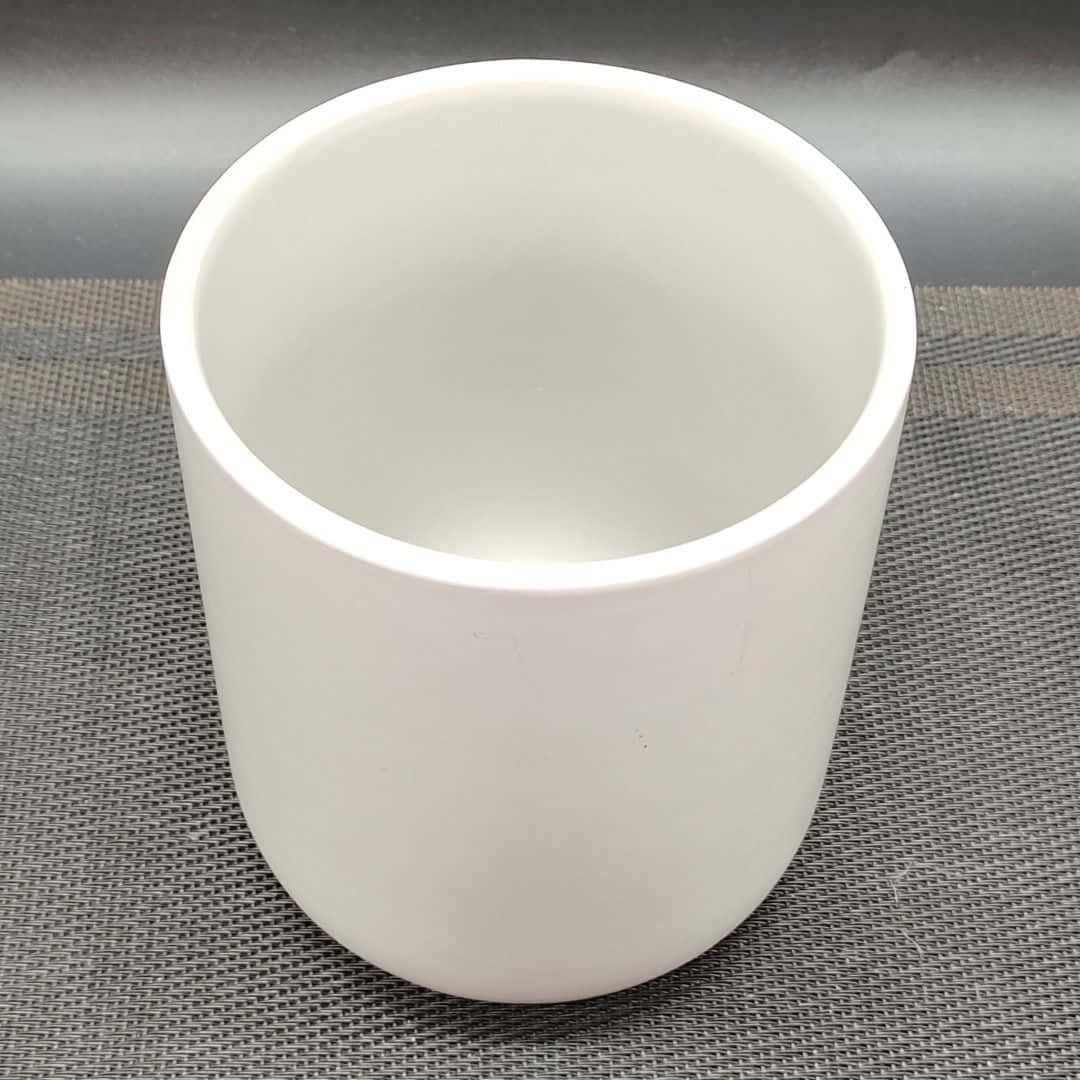 Ceramic 桌布 壁紙 — 一隻純白色的陶瓷杯在柔和的攝影棚燈光下，放置在帶有紋理的灰色墊子上。