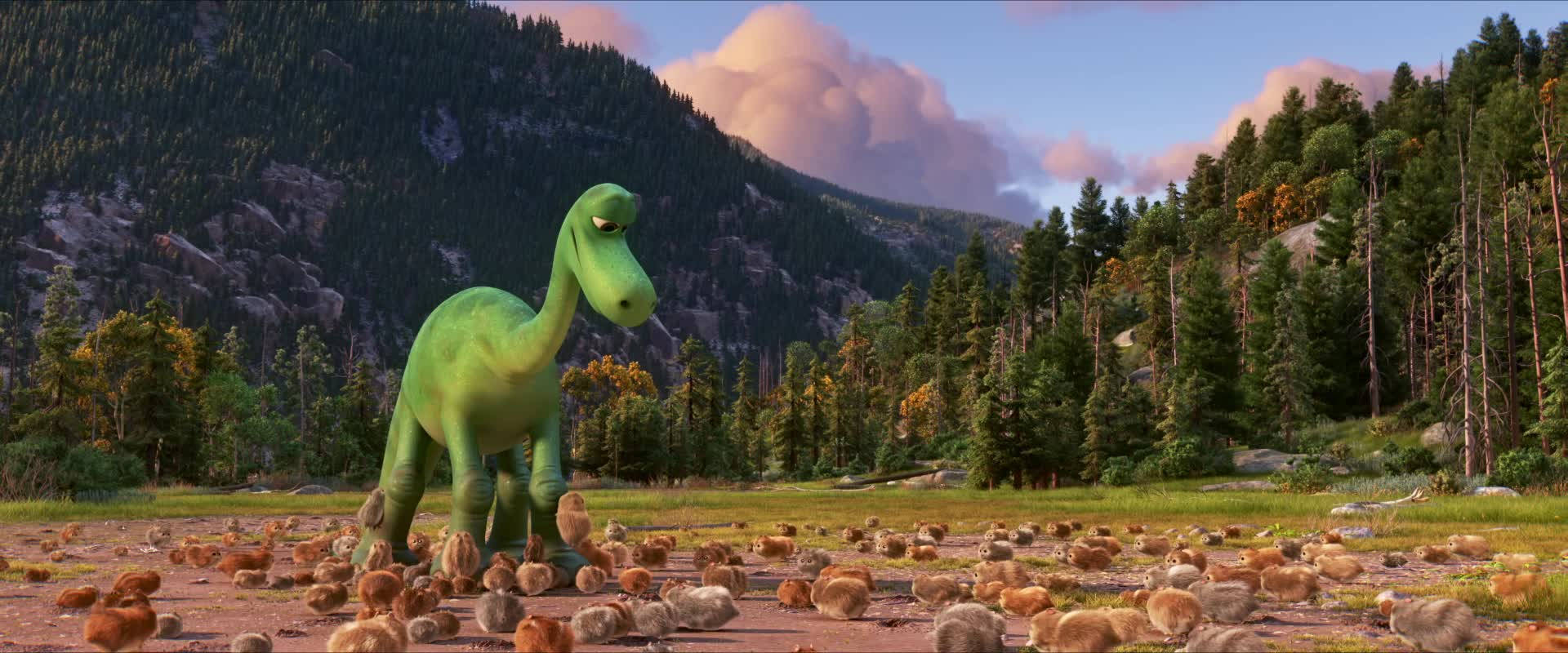 The Good Dinosaur 桌布 壁紙 — 一隻綠色動畫恐龍站在草地上，周圍有許多小雞，背景是森林覆蓋的山脈和粉紅色的雲彩。