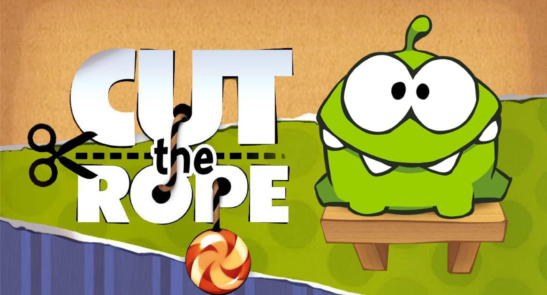 Kawaii Frog 桌布 壁紙 — 一隻綠色卡通生物坐在木凳上，旁邊是《Cut the Rope》遊戲標題，剪刀正在剪斷連著棒棒糖的繩子。
