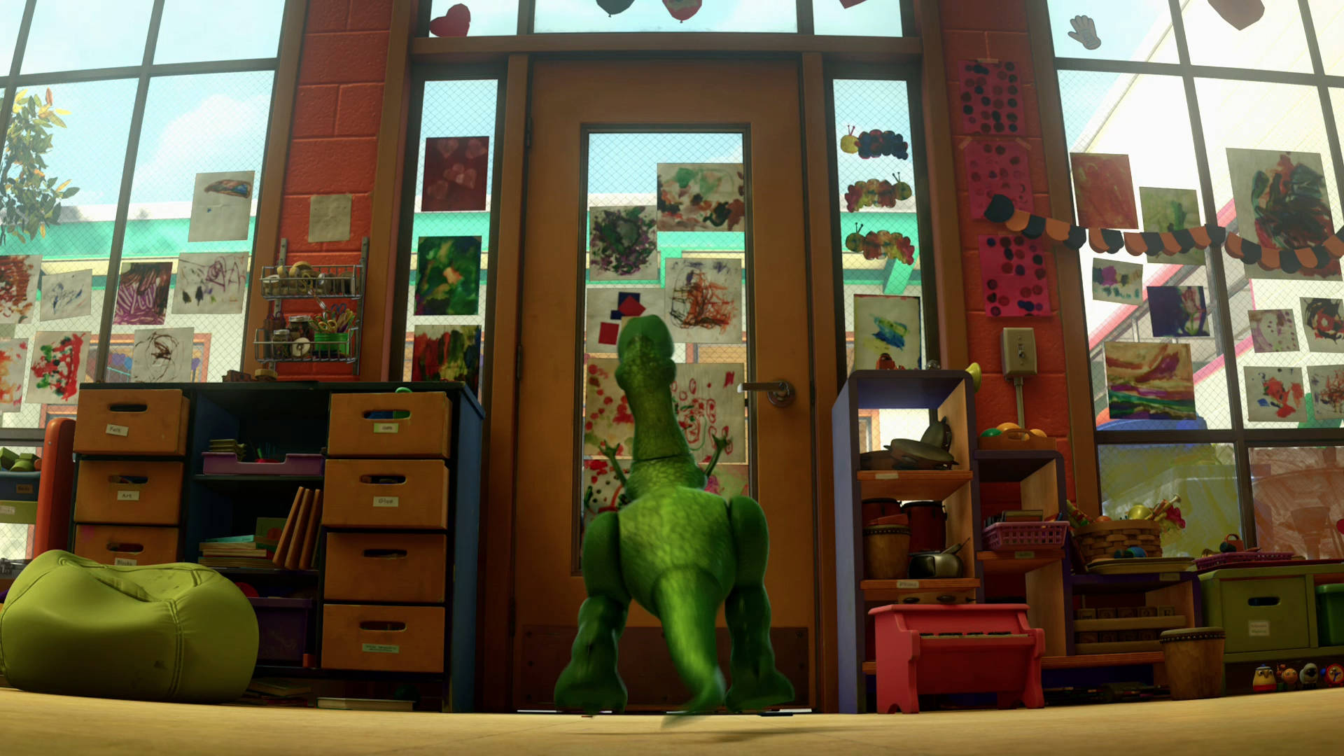 Toy Story 3 桌布 壁紙 — 一隻綠色恐龍玩具站在色彩繽紛的學前班教室門口，教室裡充滿了兒童藝術品和玩具。