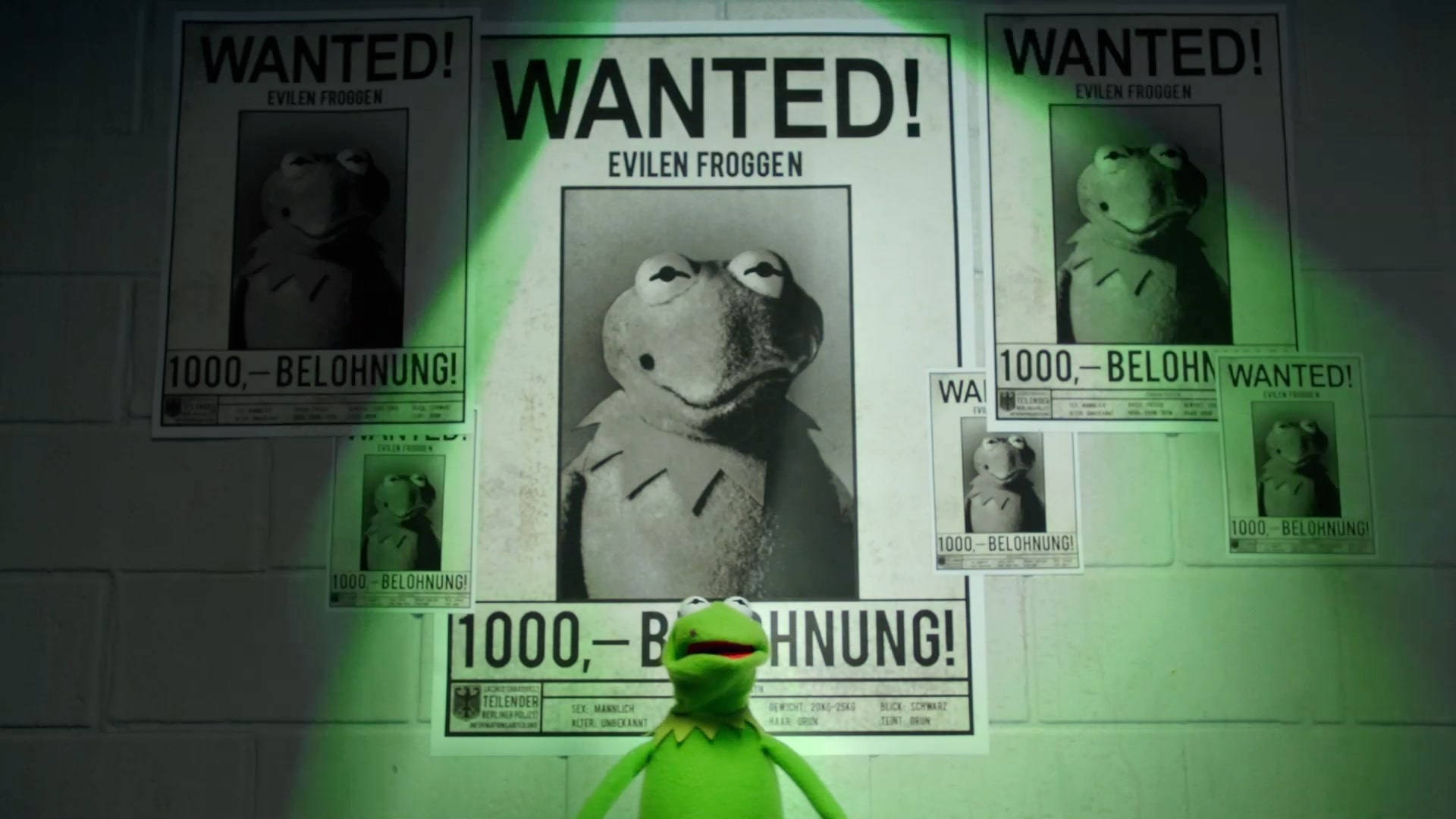 muppets 桌布 壁紙 — 一隻綠色青蛙木偶站在一面貼滿通緝海報的牆前，海報上有它自己的臉，在綠色聚光燈下。