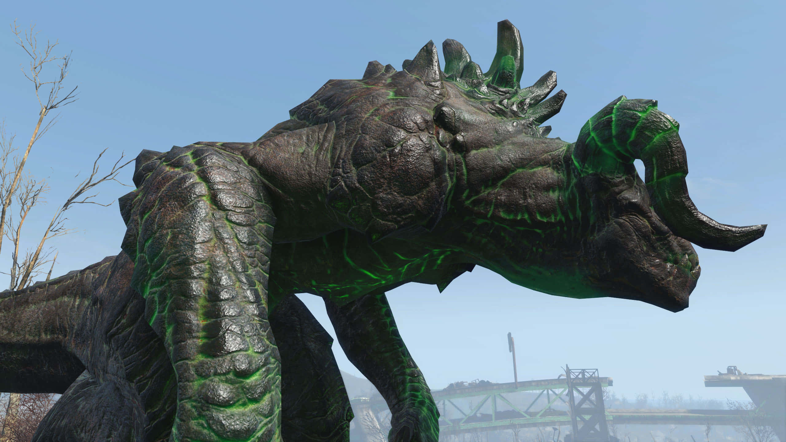 Deathclaw 桌布 壁紙 — 一隻背上有尖刺和角的巨大深綠色發光龍，在晴朗的藍天下籠罩著荒涼的景觀。