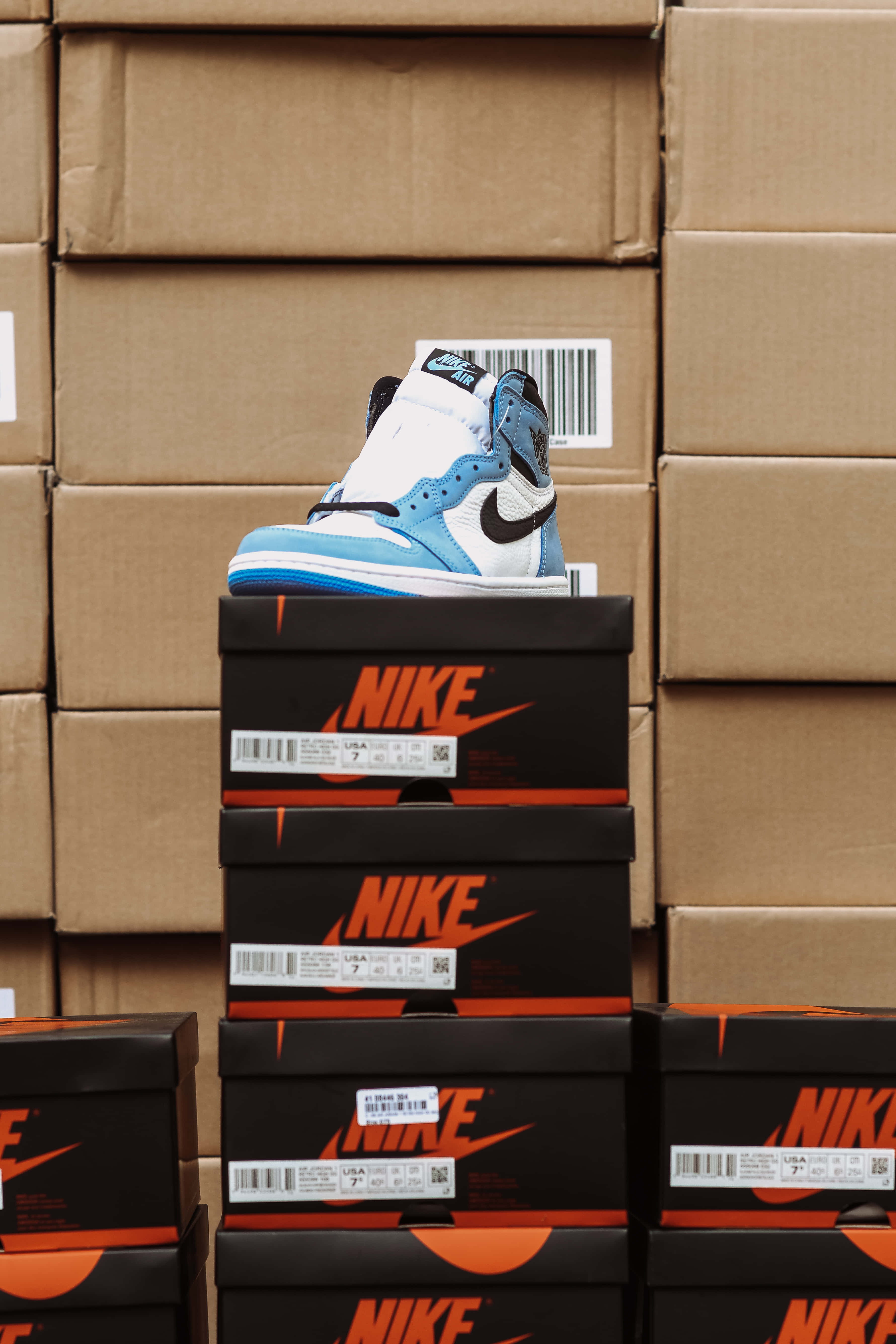 Shoe Box 桌布 壁紙 — 一隻藍白色Nike Air Jordan球鞋放在倉庫中一堆黑色Nike鞋盒上。