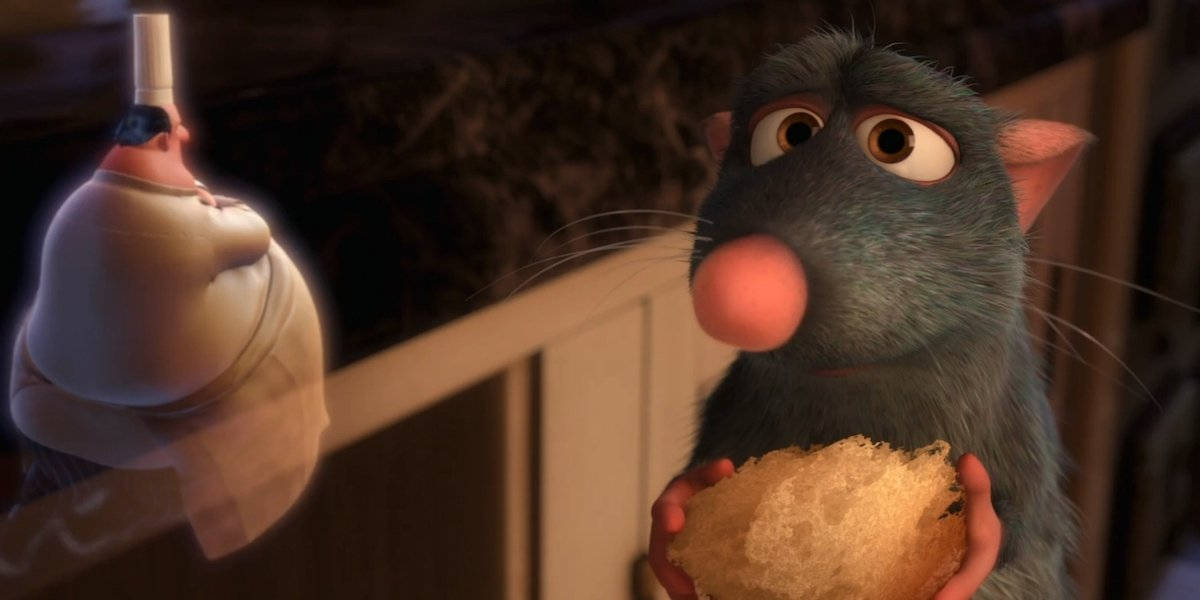 Ratatouille 桌布 壁紙 — 一隻藍色動畫老鼠睜大眼睛，在昏暗的廚房裡拿著一個麵包卷，盯著一位廚師。