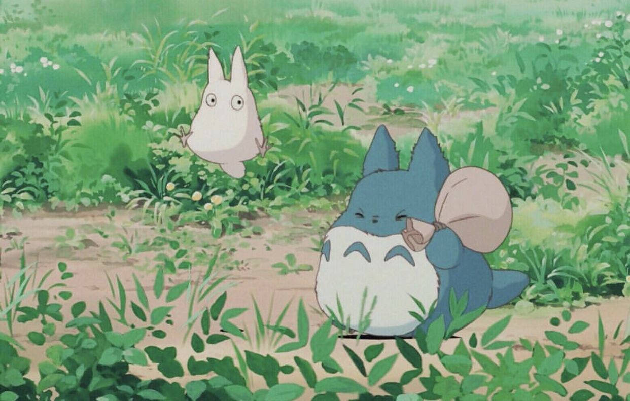 藍色龍貓和一隻白色小生物在長滿草的森林空地中。 — 龍貓 GIF 壁紙