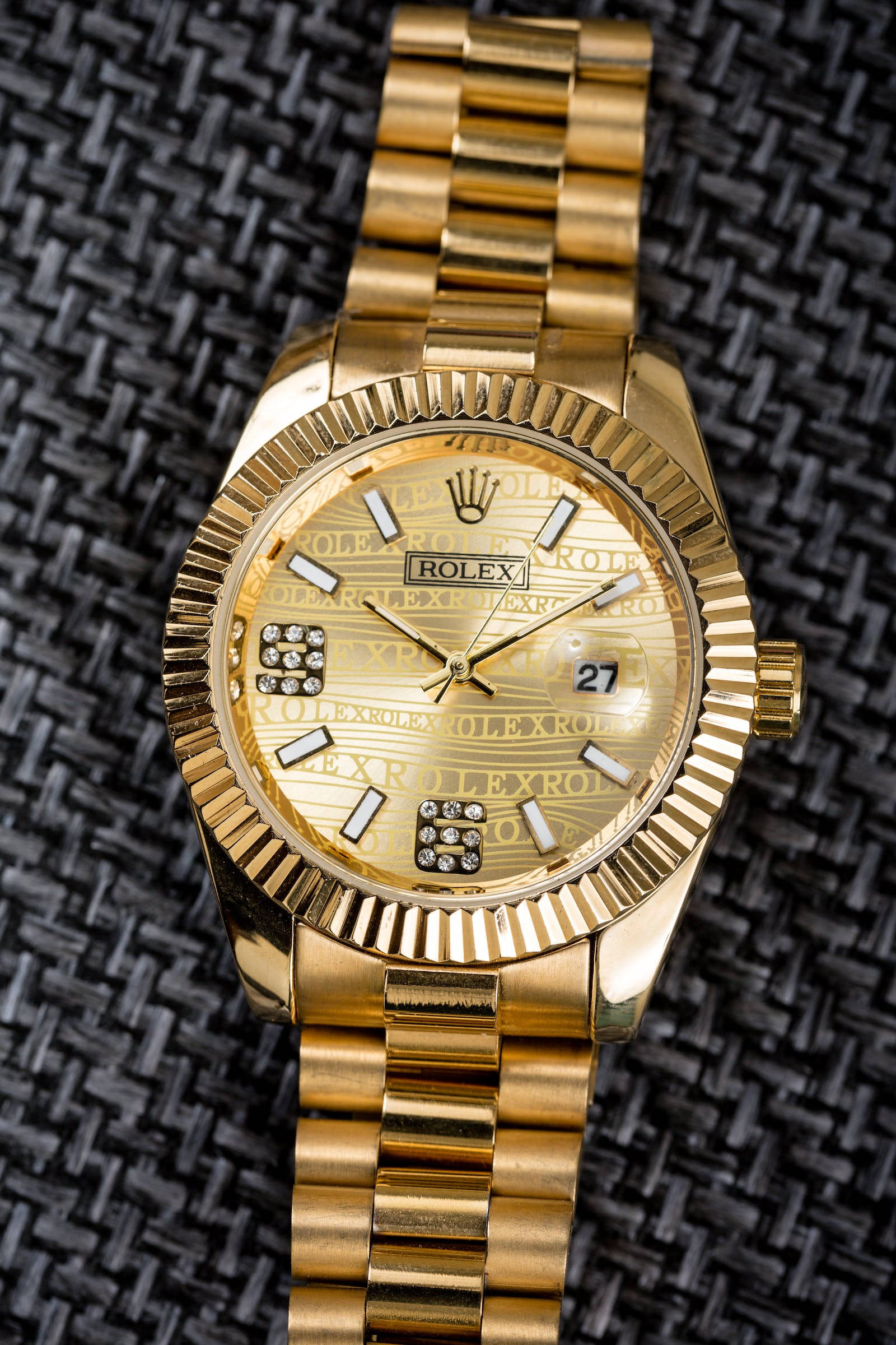 Rolex 桌布 壁紙 — 一隻豪華金色勞力士手錶，帶有鑽石小時標記，放置在深色編織布料背景上。