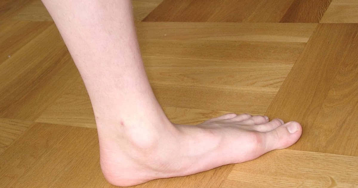 feet 桌布 壁紙 — 一隻赤腳擱在暖色調的木地板（拼花地板）上，木紋清晰可見，自然光線充足。