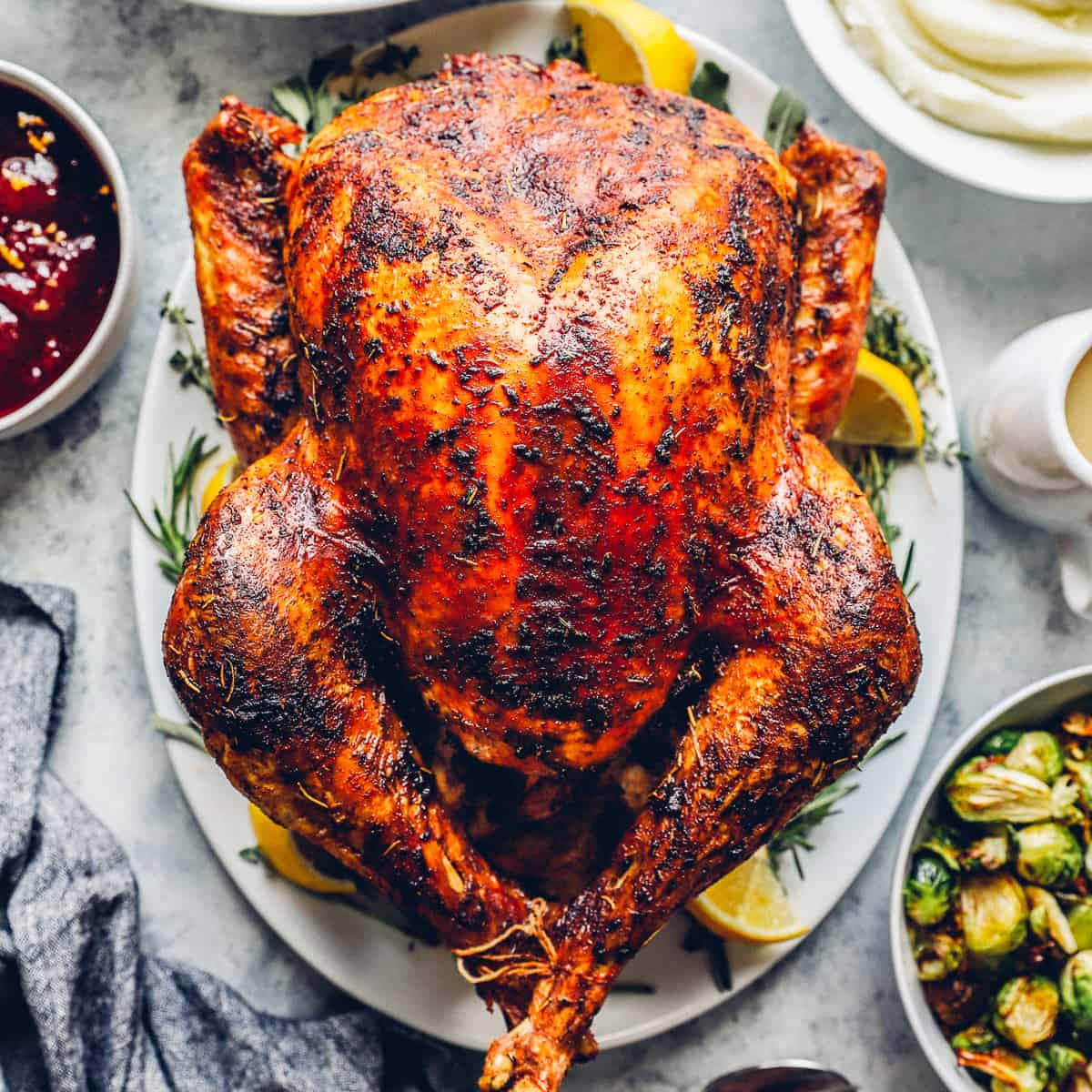 Turkey Happy Thanksgiving 桌布 壁紙 — 一隻金黃色的烤火雞，外皮酥脆，放在盤子中央，周圍有蔓越莓醬、烤抱子甘藍和馬鈴薯泥。