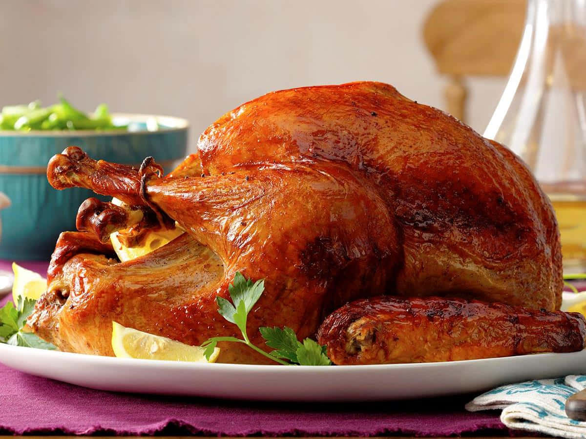 Turkey Happy Thanksgiving 桌布 壁紙 — 一隻金黃色的烤火雞在白色托盤上閃閃發光，飾以歐芹和檸檬角。