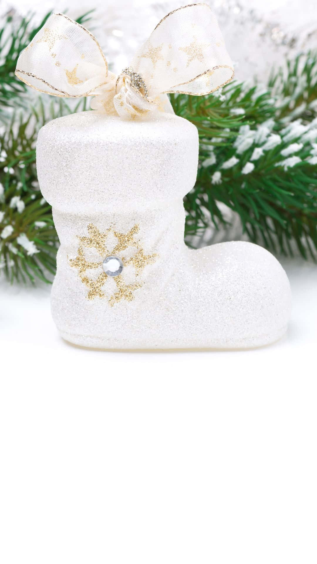 聖誕節 桌布 壁紙 — 一隻閃閃發光的白色聖誕襪，飾有金色雪花和蝴蝶結，靠在白雪覆蓋的松樹枝上。