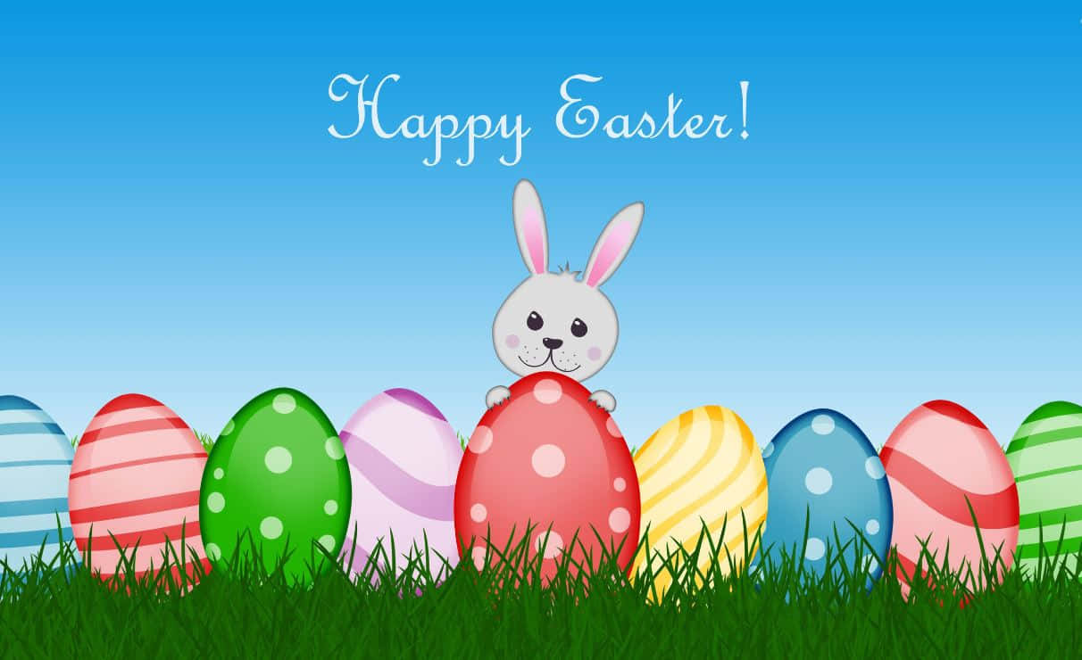 Cute Easter 桌布 壁紙 — 一隻開心的卡通兔子在一排色彩繽紛、有圖案的復活蛋上方探頭，這些蛋放在鮮綠色的草地上，背景是晴朗的藍天。