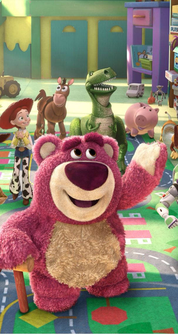 Toy Story 3 桌布 壁紙 — 一隻開心的粉紅色泰迪熊在一個色彩繽紛、充滿玩具的遊戲室裡，和其他生動的玩具一起開心地揮手。