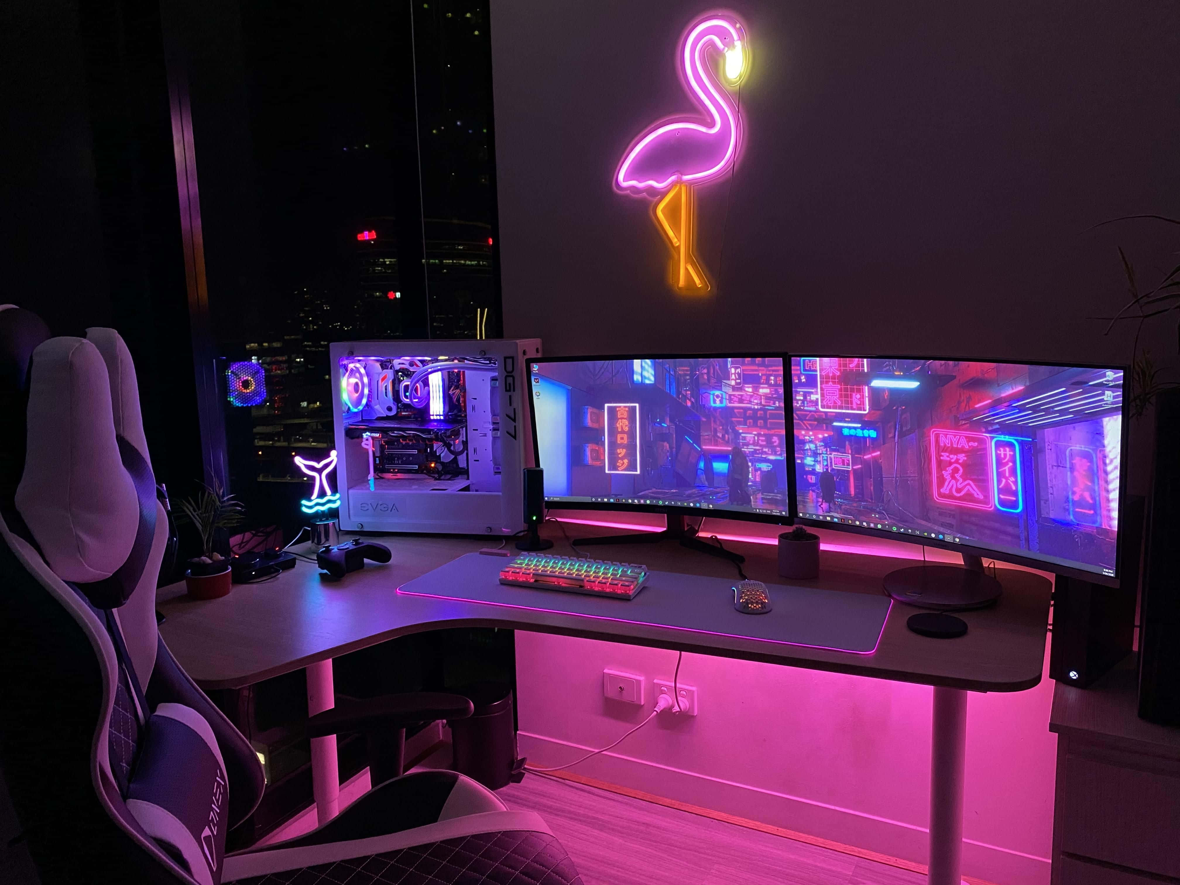 Gaming Pc Setup 桌布 壁紙 — 一隻霓虹燈火烈鳥裝飾著一個黑暗的電競設置，配備雙顯示器，顯示著賽博龐克城市景觀，以及一個發光的電腦機箱。