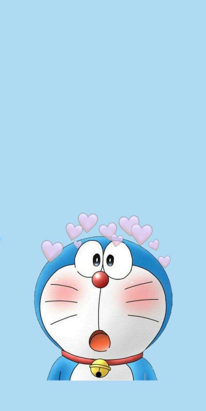 Doraemon 桌布 壁紙 — 一隻驚訝的藍色機器貓，頭頂上有粉紅色愛心漂浮在淺藍色背景上。