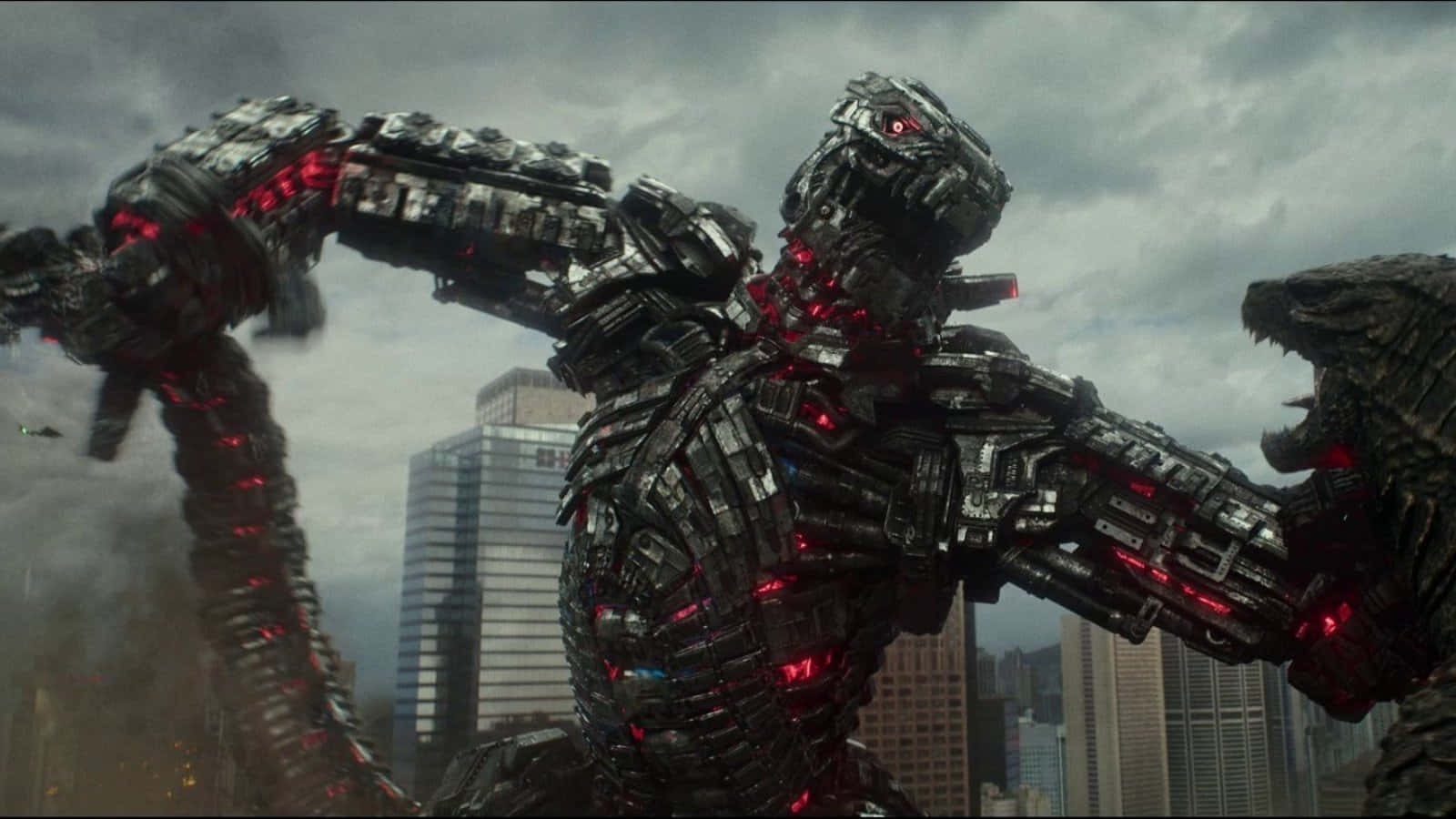 Robot Godzilla 桌布 壁紙 — 一隻高聳的生物機械哥吉拉，帶有發光的紅色電路，在煙霧瀰漫的城市天際線下，陰雲密佈的天空中戰鬥。