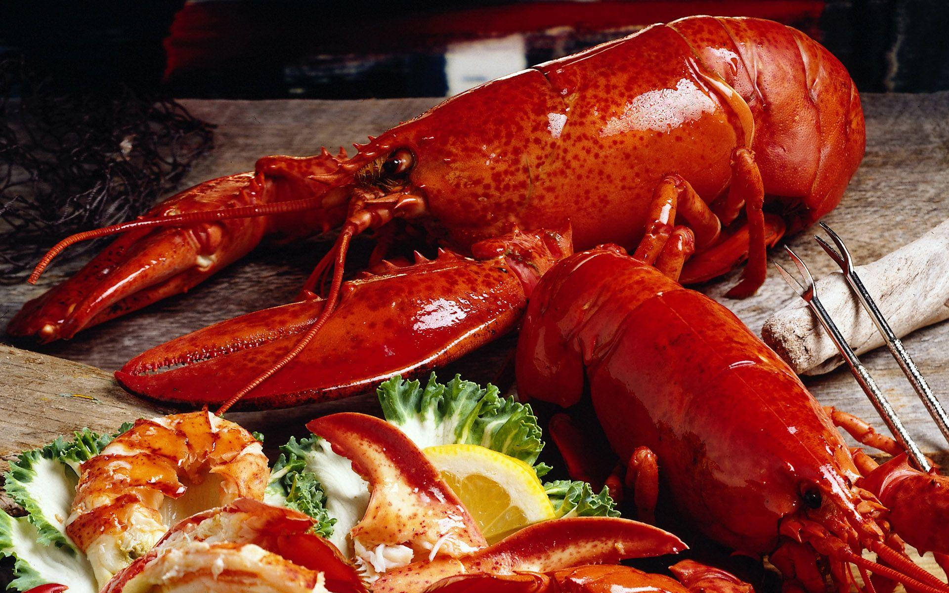 Lobster 桌布 壁紙 — 一隻鮮紅色的熟龍蝦，帶有爪和尾巴，放在質樸的木板上，旁邊是新鮮蔬菜和檸檬。