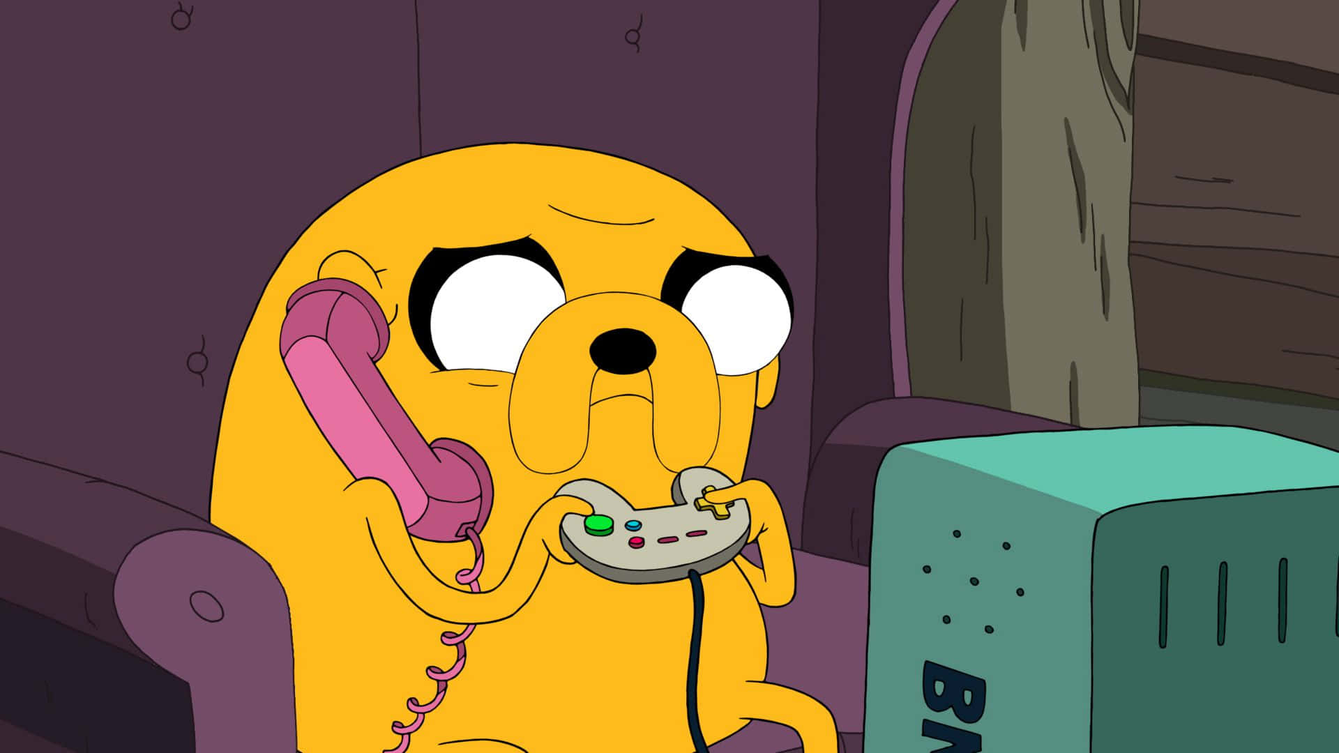 Adventure Time Cute 桌布 壁紙 — 一隻黃色卡通狗坐在紫色沙發上，拿著粉紅色電話和遊戲控制器，表情驚訝。