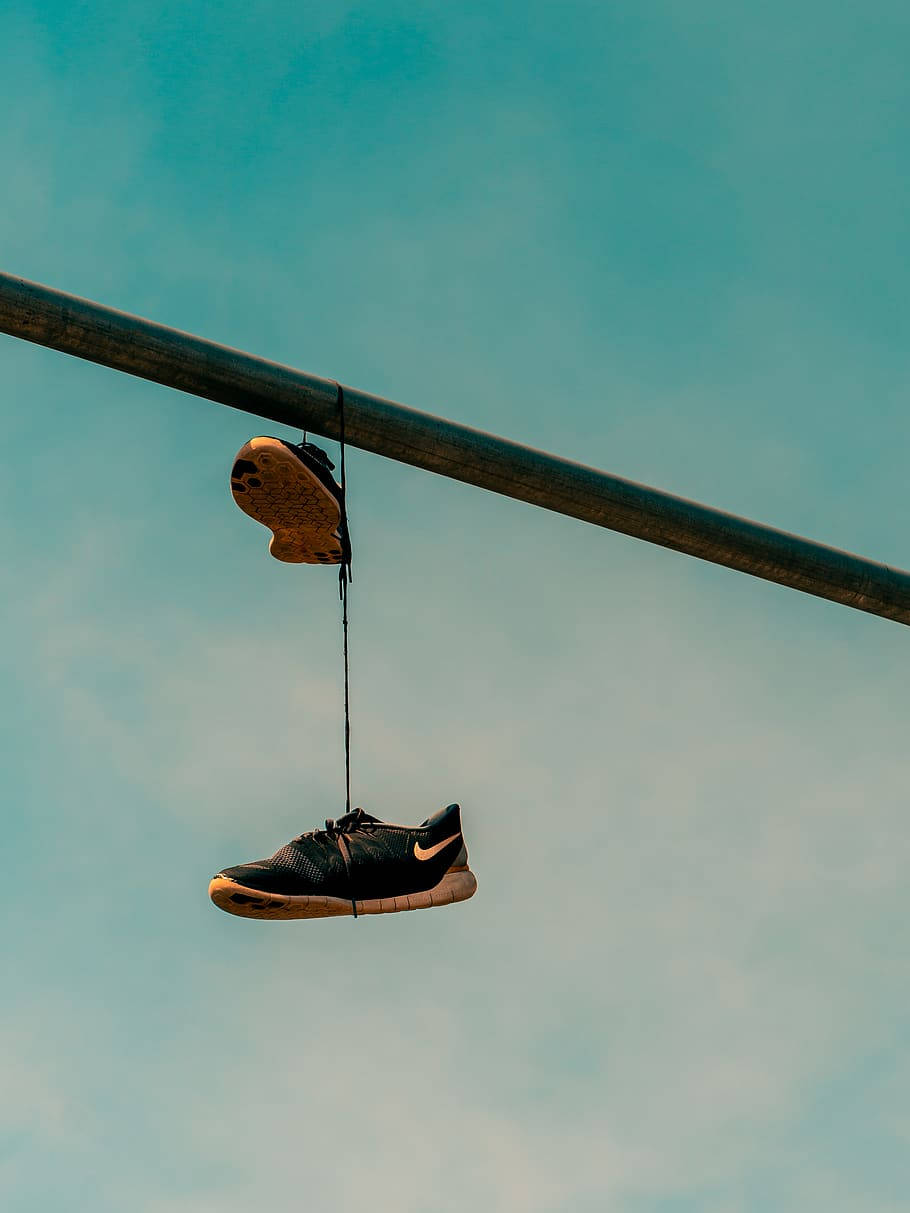 Nike Shoes 桌布 壁紙 — 一隻黑色運動鞋用細繩掛在金屬桿上，背景是淡藍色天空。