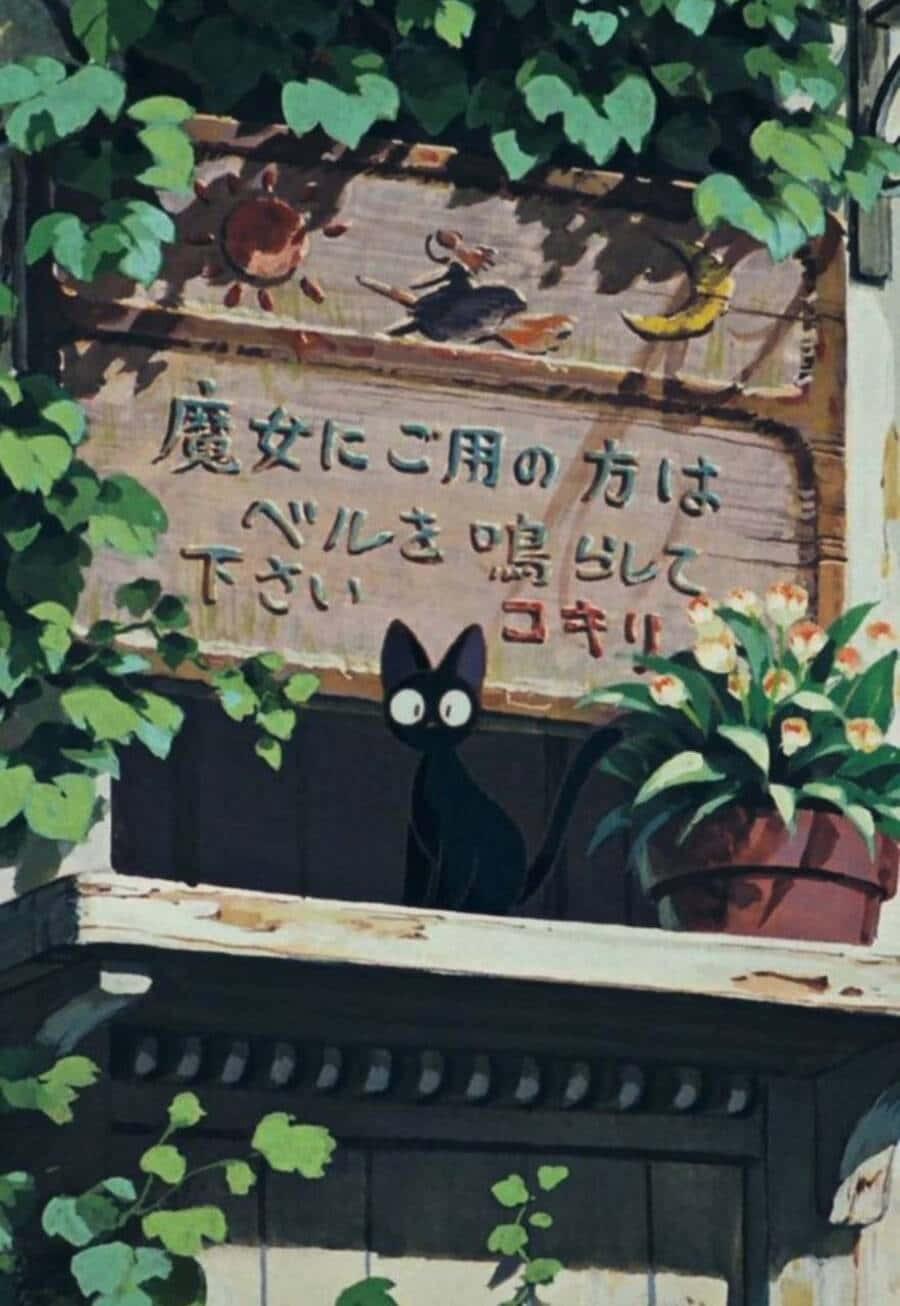 Jiji Cat 桌布 壁紙 — 一隻黑貓睜大眼睛，從一個帶有日文字句及太陽、月亮、鳥類插圖的木牌後面探頭出來，周圍是茂密的綠葉和一盆花卉。