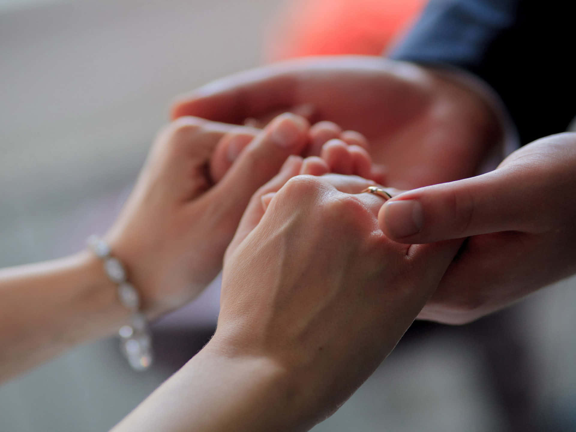 Holding Hands 桌布 壁紙 — 一雙交織的手的特寫，金戒指戴在手指上，象徵著溫柔的承諾時刻。