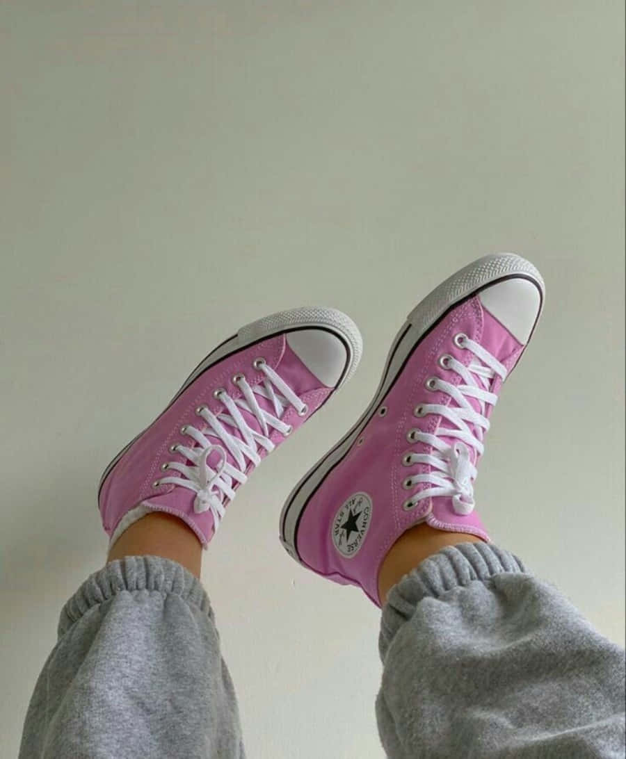 Pink Shoes 桌布 壁紙 — 一雙亮粉紅色Converse運動鞋，搭配白色鞋帶和橡膠鞋頭，與灰色運動褲一起，背景是素色牆壁。