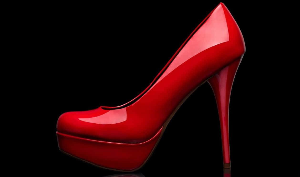 Red High Heels 桌布 壁紙 — 一雙亮面紅色厚底細跟高跟鞋在帶有反射表面的漆黑背景上閃耀。
