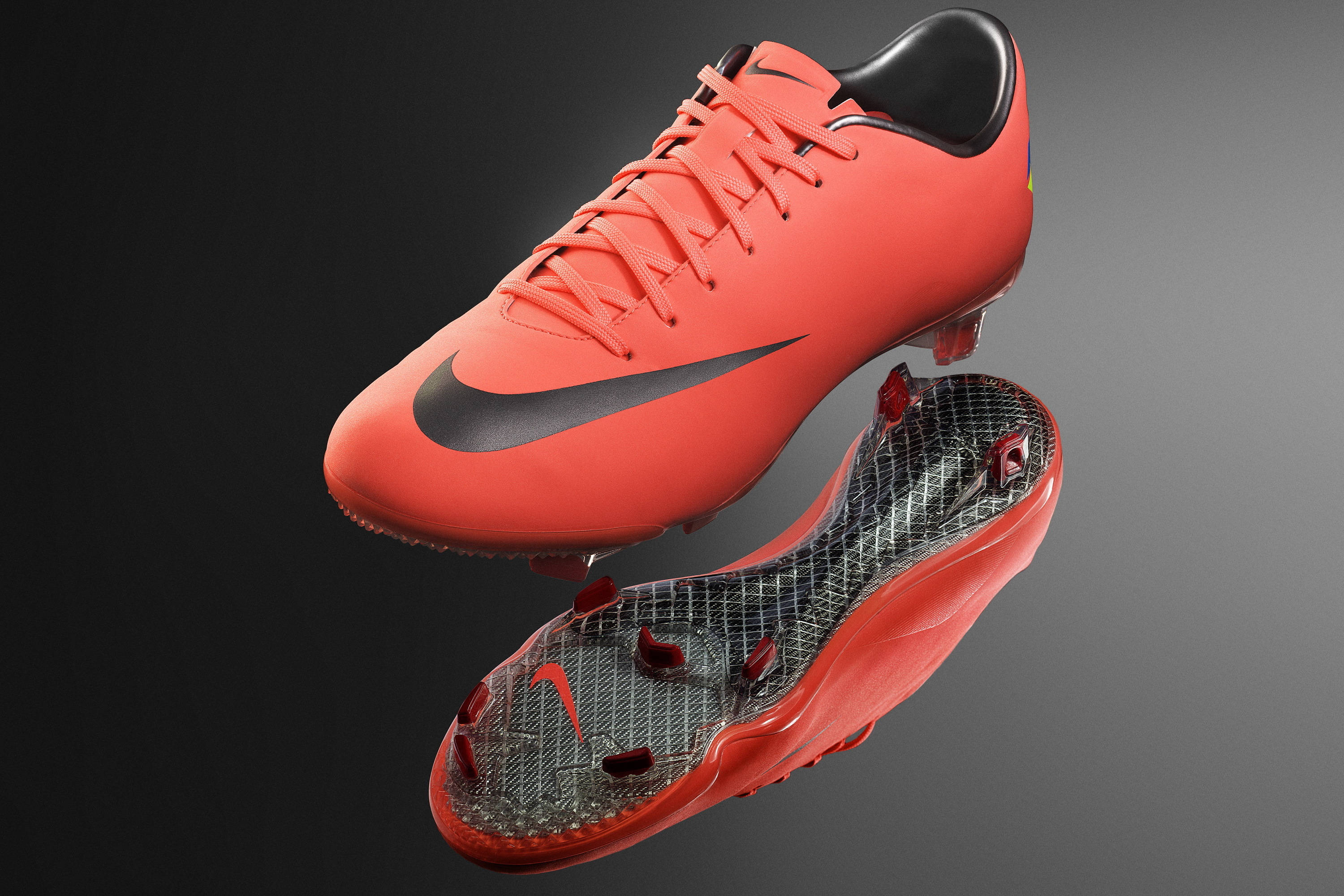 Nike Shoes 桌布 壁紙 — 一雙充滿活力的橙色Nike足球靴，帶有黑色點綴，在深色漸變背景中懸浮，露出其紋理鞋底。