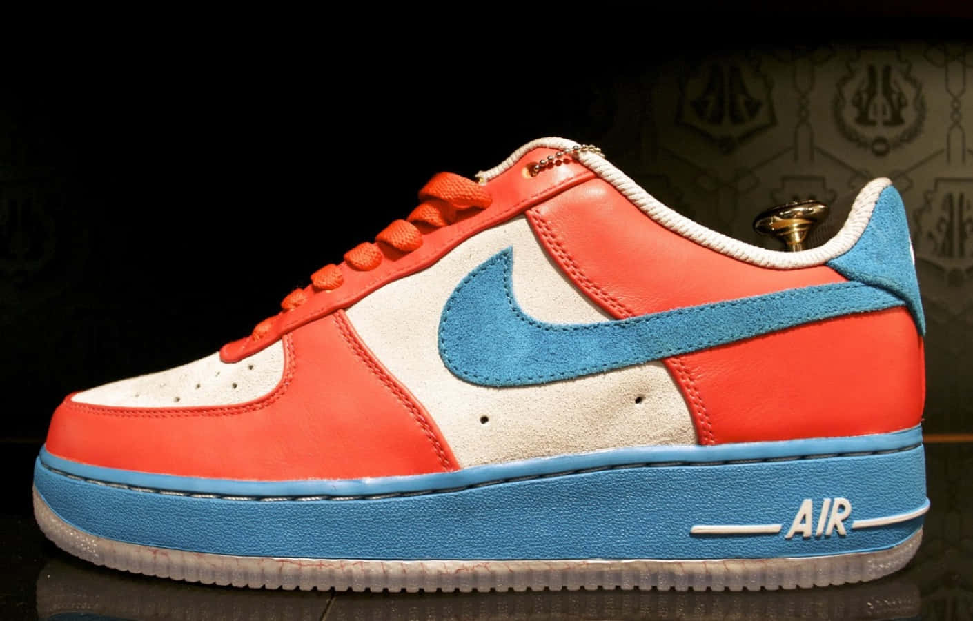 Nike 桌布 壁紙 — 一雙充滿活力的紅白藍Nike Air Force 1運動鞋，帶有金色鞋跟標籤，展示在深色華麗的壁紙背景上。