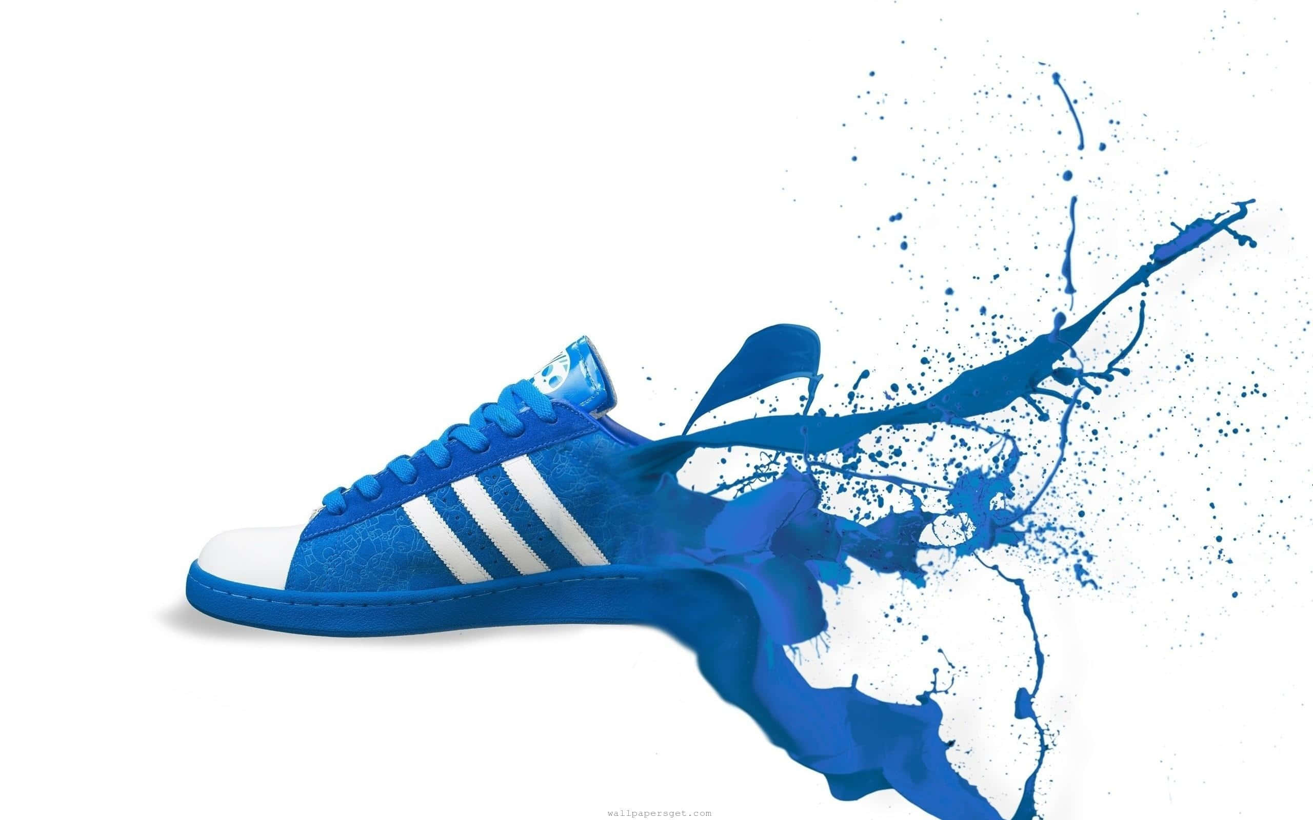 Footwear Design 桌布 壁紙 — 一雙充滿活力的藍色 Adidas 運動鞋在純白背景上爆發出動態的顏料飛濺效果。