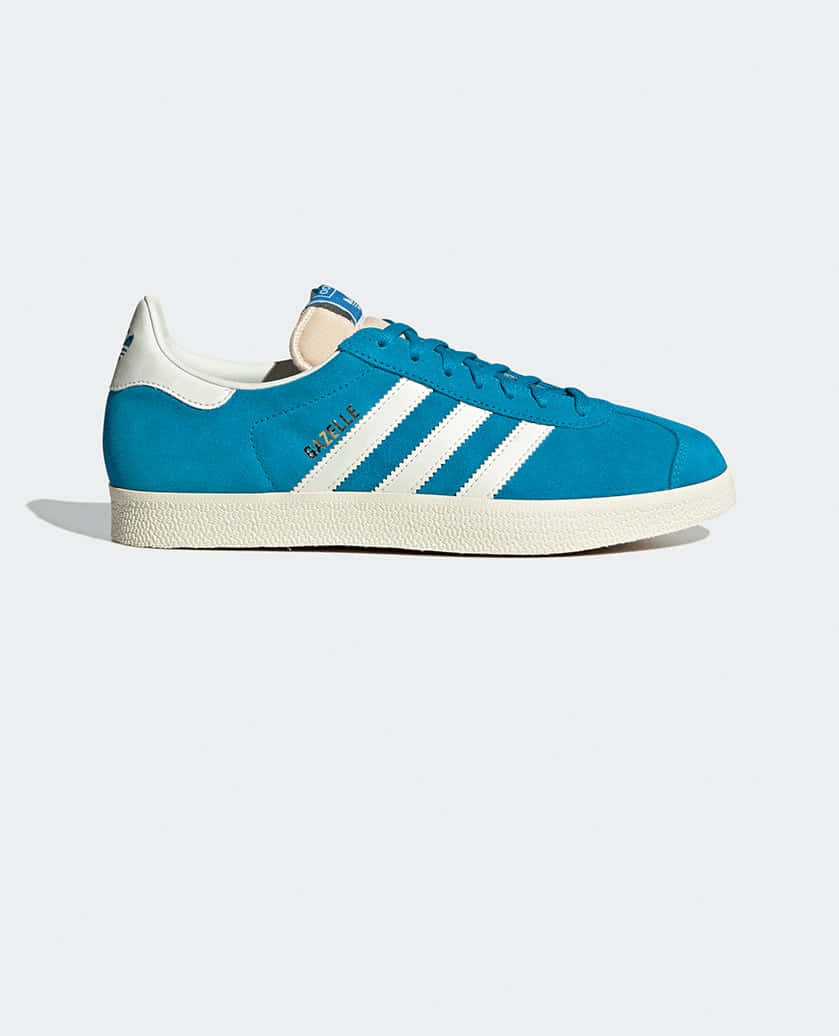 愛迪達 桌布 壁紙 — 一雙充滿活力的藍色 adidas Gazelle 運動鞋，帶有白色條紋和鞋帶，在乾淨的攝影棚燈光下展示。