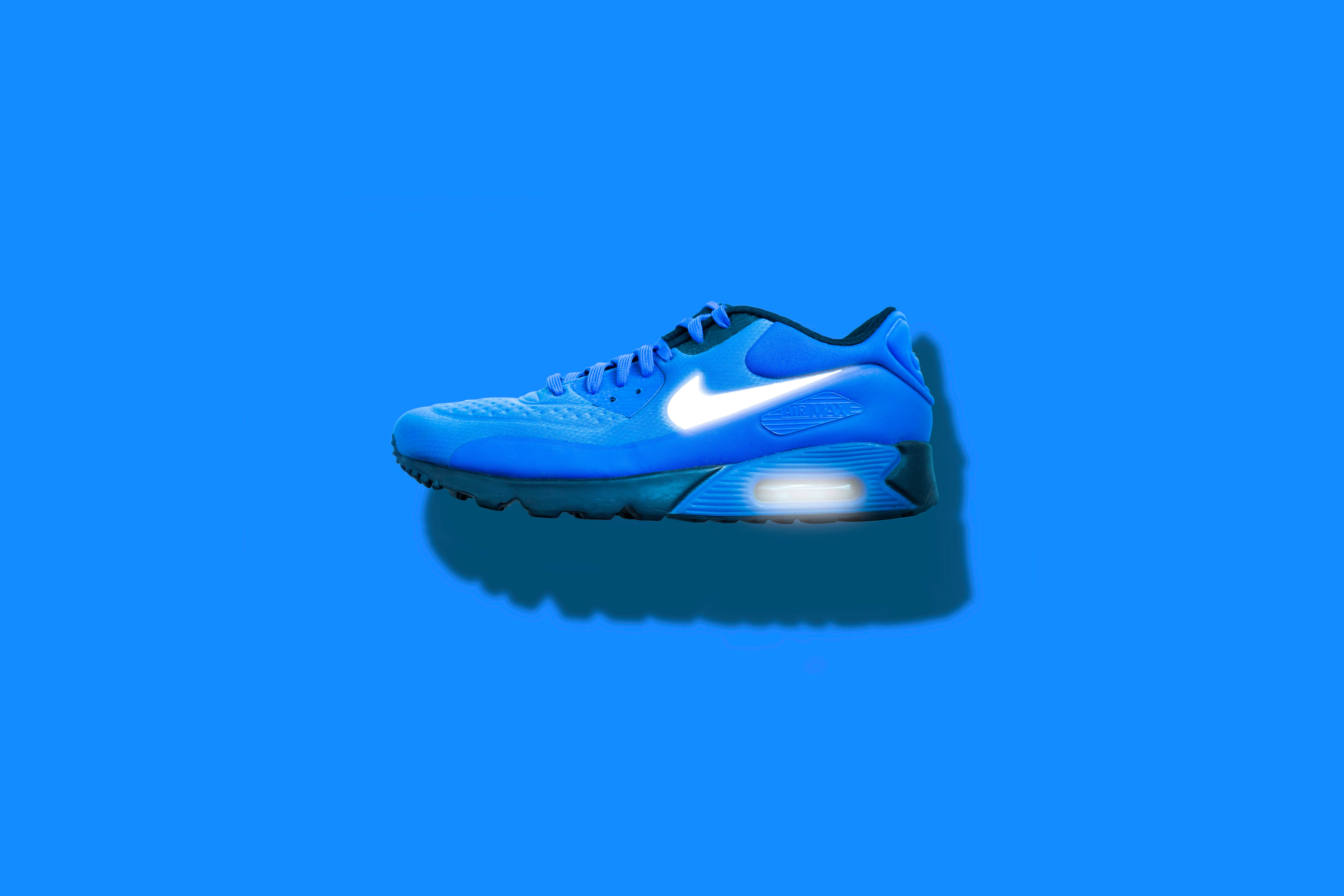 Nike 桌布 壁紙 — 一雙充滿活力的藍色 Nike Air Max 運動鞋，帶有發光鞋底，居中放置在純藍色背景上。