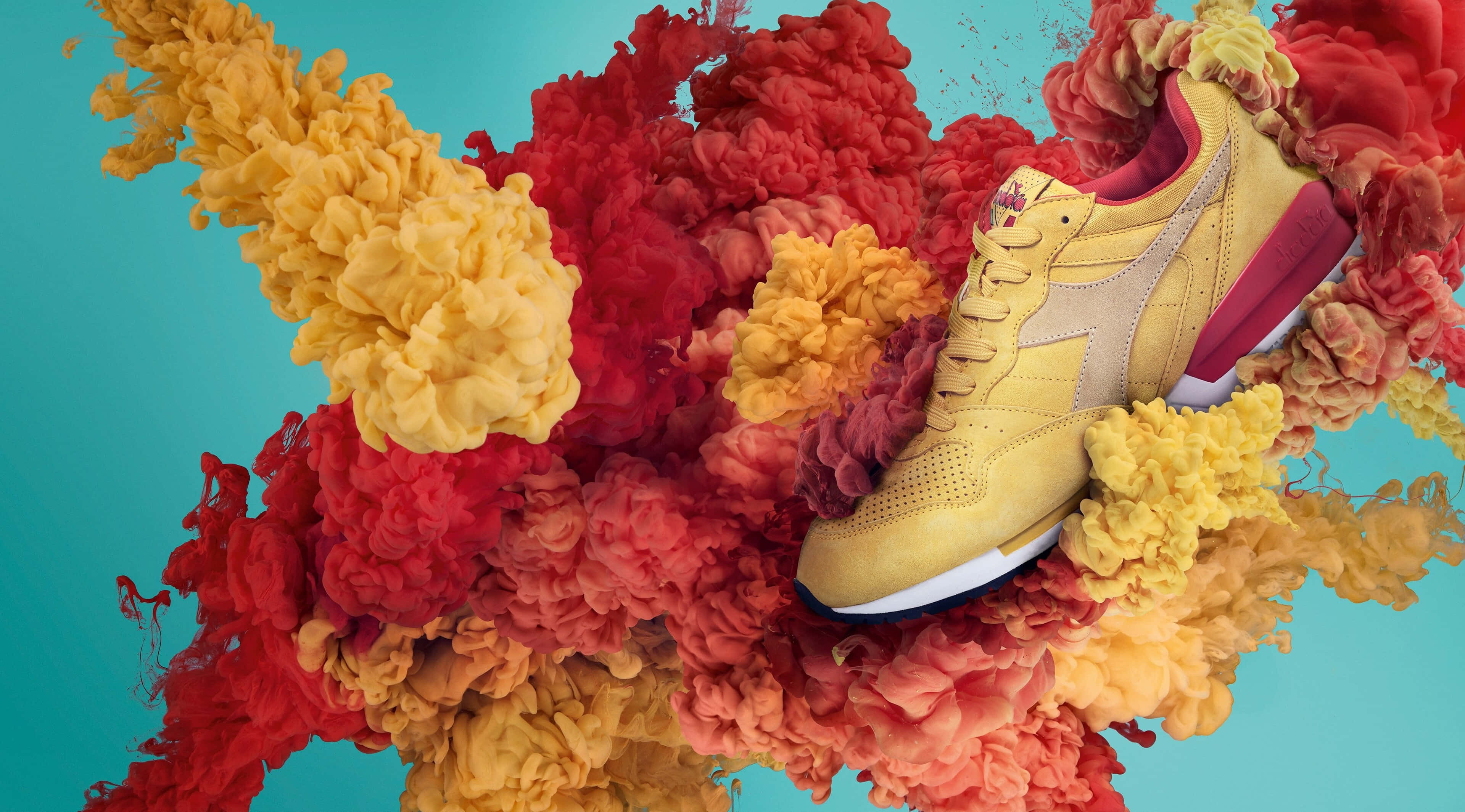 Sneaker 桌布 壁紙 — 一雙充滿活力的黃色運動鞋從旋轉的紅色和橙色墨水中浮現，背景為青綠色。