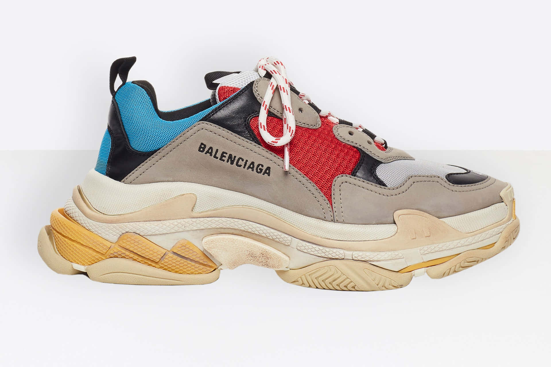 巴黎世家 桌布 壁紙 — 一雙大膽的Balenciaga運動鞋，搭配厚實的分層鞋底，以及鮮豔的紅色、藍色和米色面板，置於純白背景上。