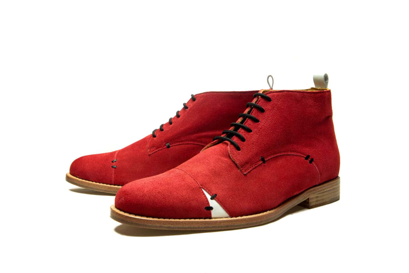 Red Shoes 桌布 壁紙 — 一雙大膽的紅色麂皮查卡靴，配有黑色鞋帶和白色鞋頭裝飾，背景為純白色。