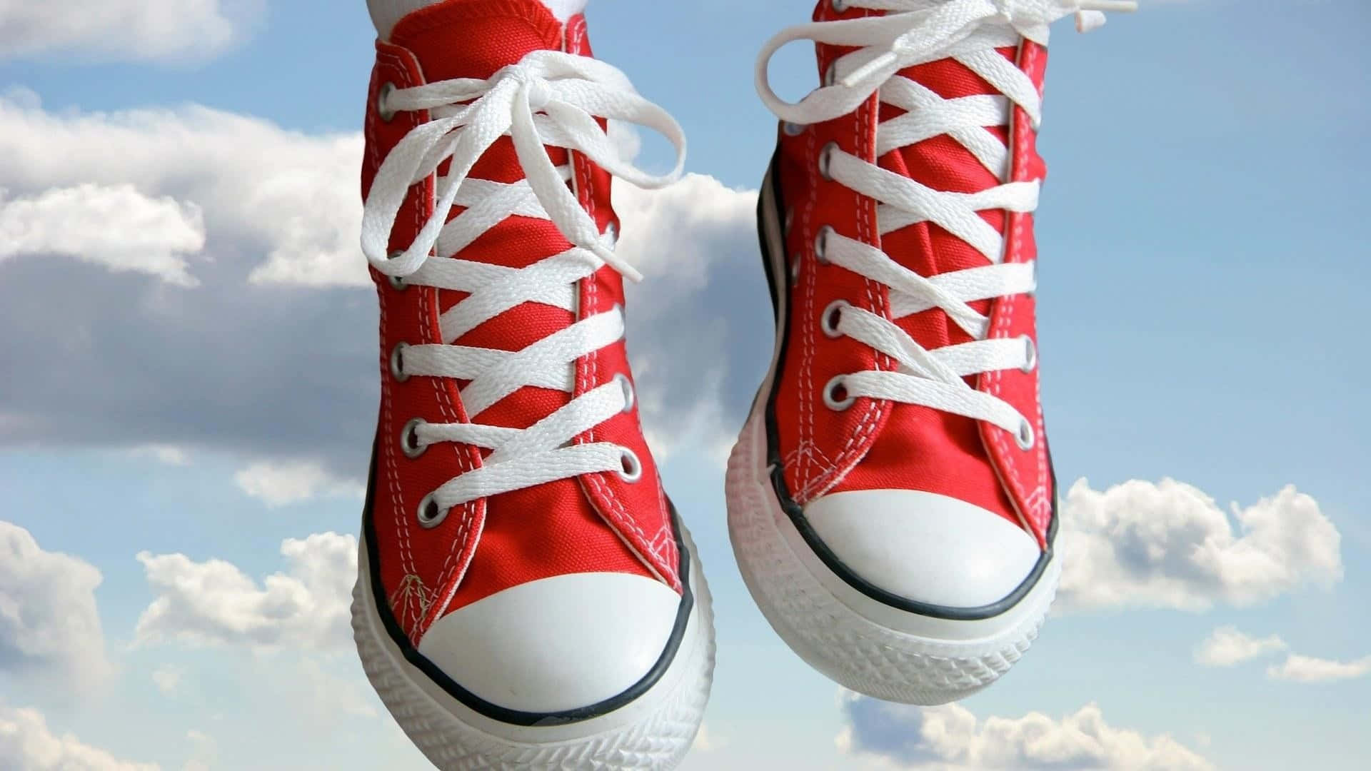Red Shoes 桌布 壁紙 — 一雙帶有白色鞋帶的紅色高筒運動鞋在明亮的藍天和蓬鬆的白雲中漂浮。