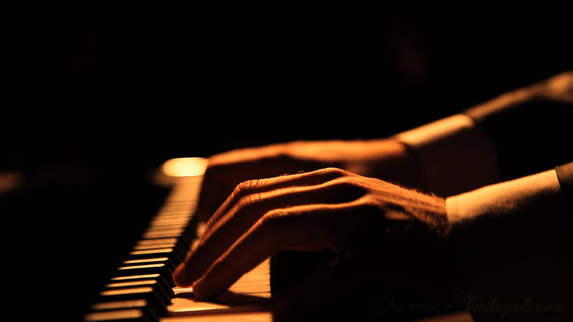 Beautiful Music 桌布 壁紙 — 一雙手在溫暖的金色燈光下，於深色背景上彈奏鋼琴琴鍵。