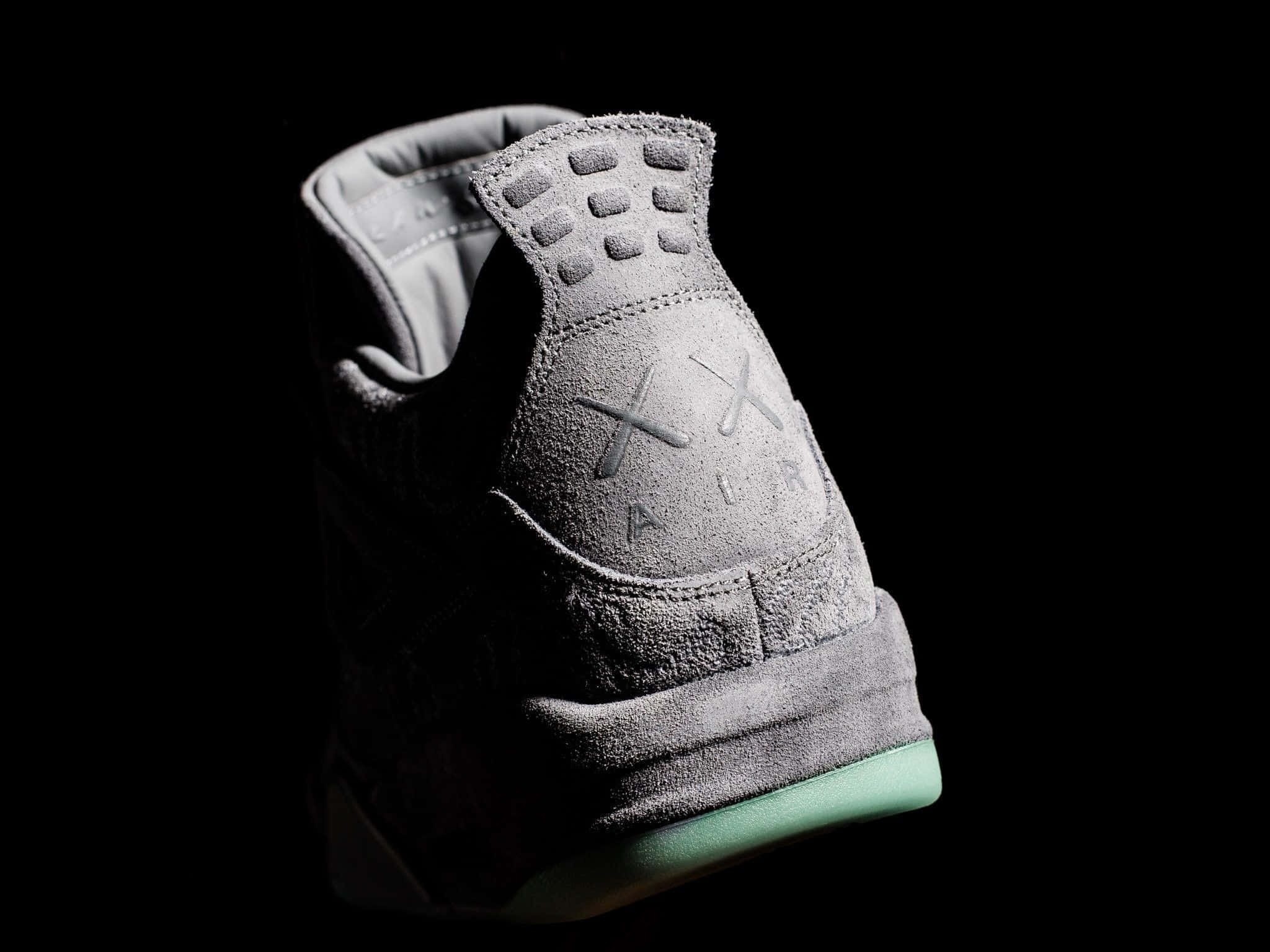 Kaws X Air Jordan 桌布 壁紙 — 一雙時尚的灰色麂皮運動鞋搭配薄荷綠色鞋底，在純黑色背景上的戲劇性聚光燈下閃耀。
