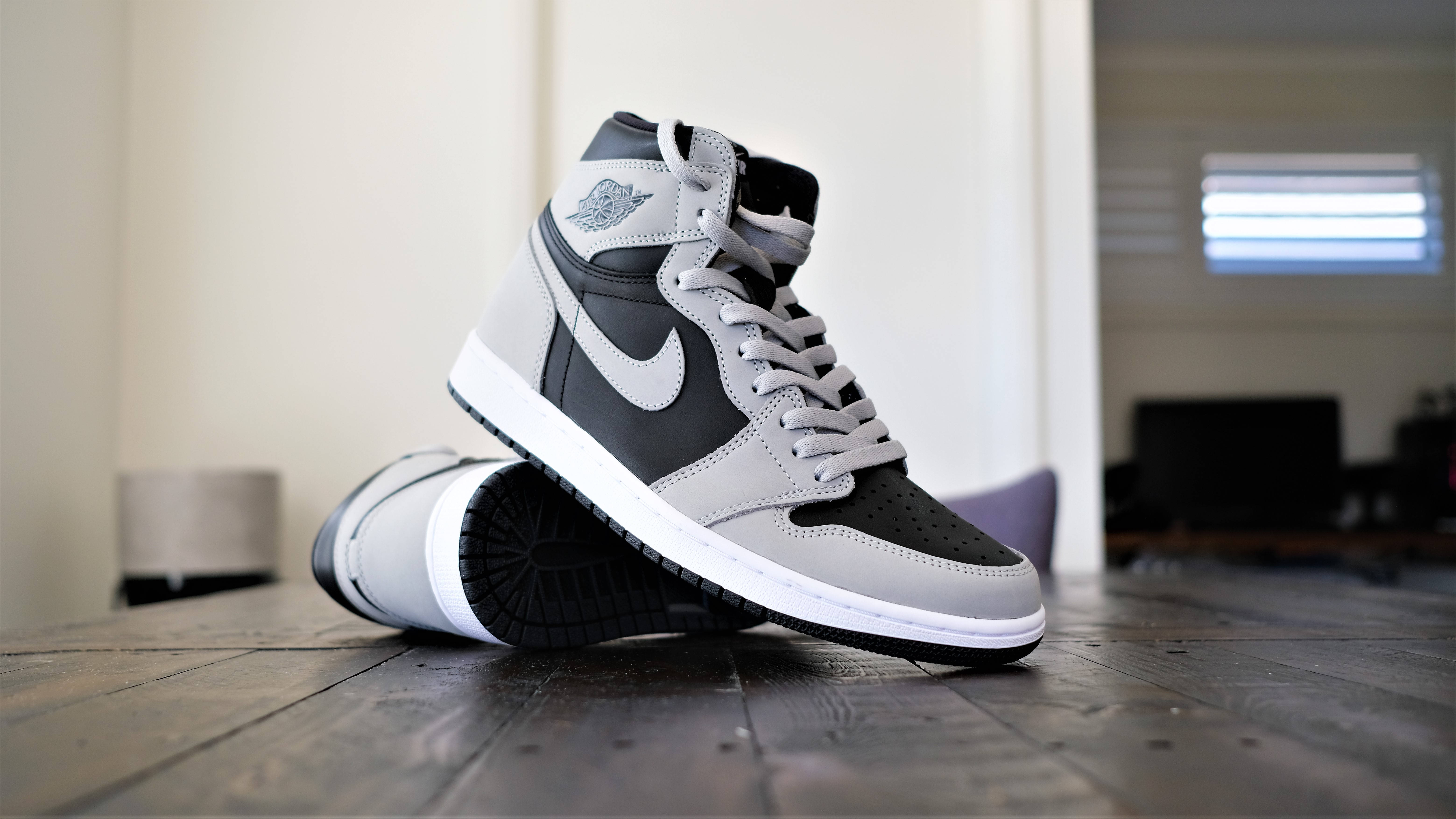 cool shoe 桌布 壁紙 — 一雙時尚的灰黑色高筒運動鞋放在室內柔和光線下的深色木地板上。
