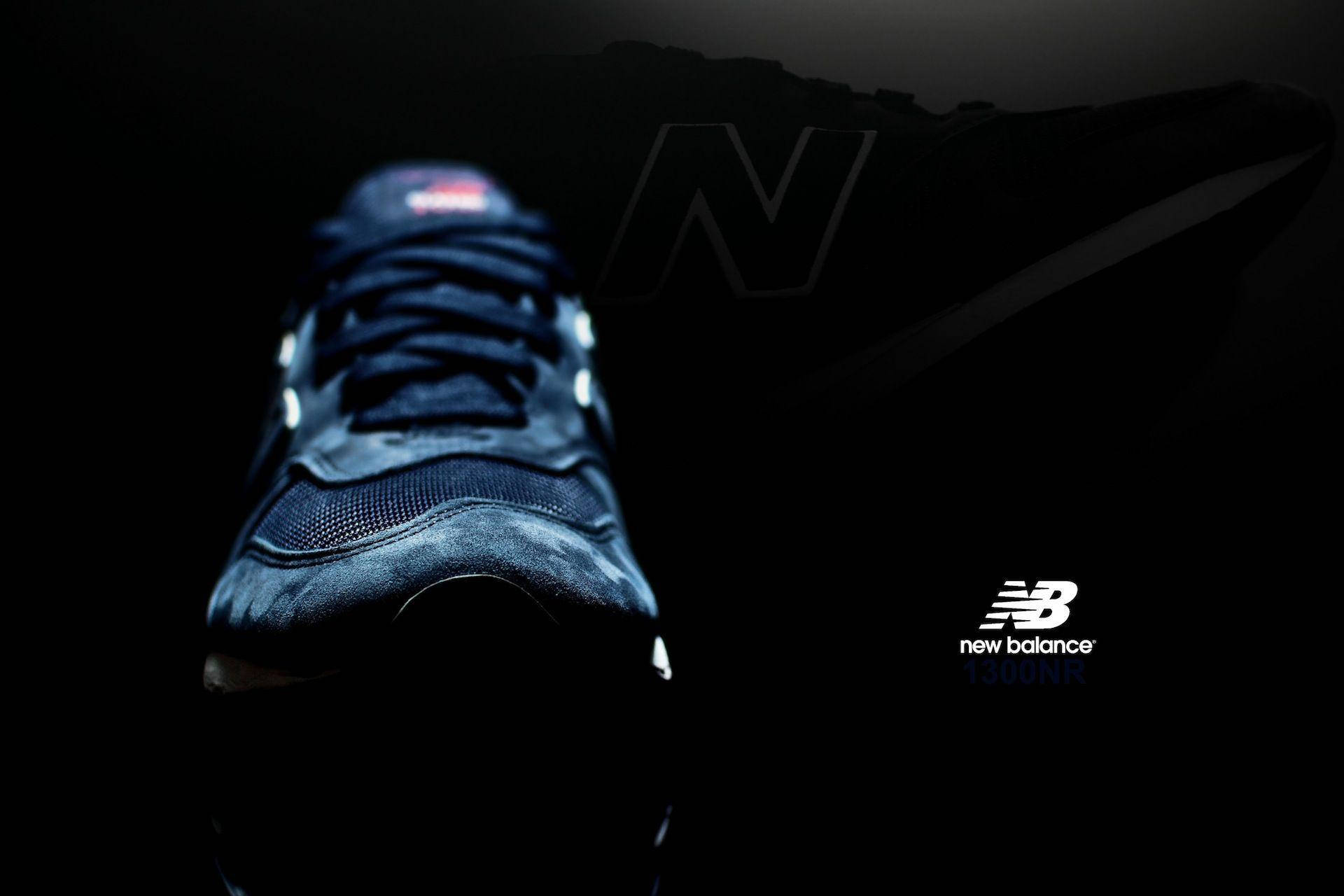 New 桌布 壁紙 — 一雙時尚的藍色New Balance運動鞋在黑色背景上，帶有微妙的品牌標誌，在戲劇性的聚光燈下閃耀。