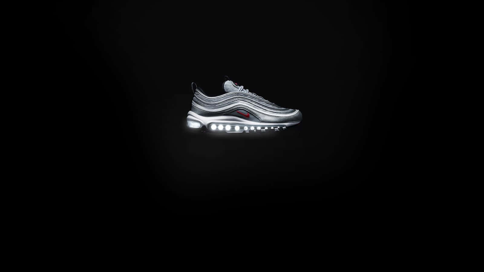 Black Air Force 桌布 壁紙 — 一雙時尚的銀色 Nike Air Max 97 運動鞋在純黑色背景下，發光的氣墊單元閃耀著光芒。