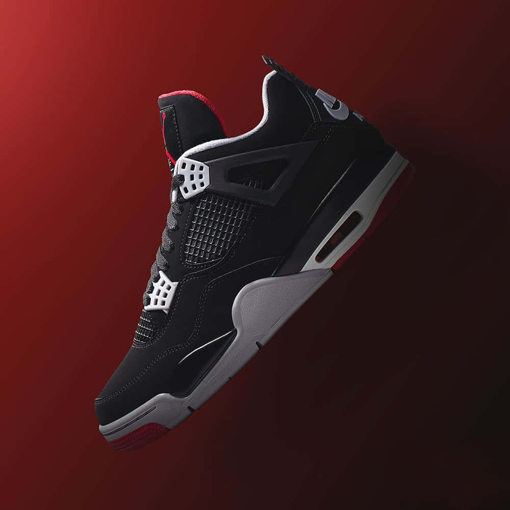 鞋子 桌布 壁紙 — 一雙時尚的黑紅Jordan 4運動鞋漂浮在漸層深紅色背景上，帶有戲劇性的燈光效果。