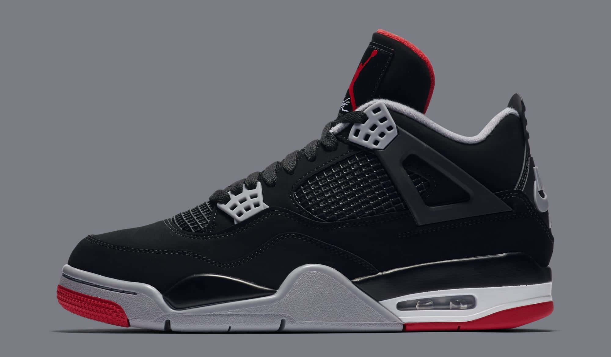 Jordan 4 桌布 壁紙 — 一雙時尚的黑色 Jordan 4 運動鞋，帶有紅色點綴和銀色細節，在灰色背景上以側面展示。