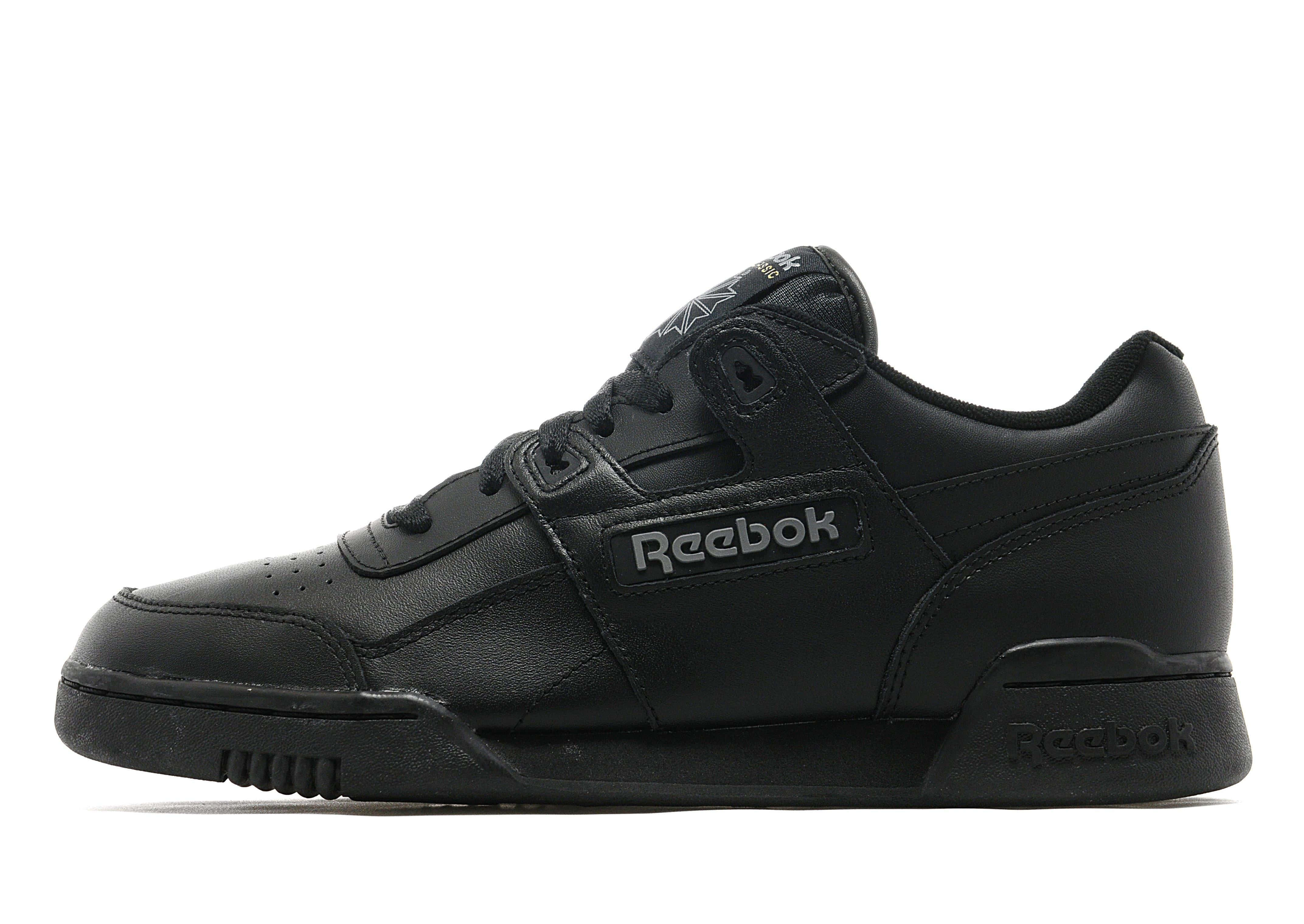 Reebok 桌布 壁紙 — 一雙時尚的黑色 Reebok 運動鞋，帶有銀色品牌標誌，在白色背景下的乾淨工作室燈光中展示。