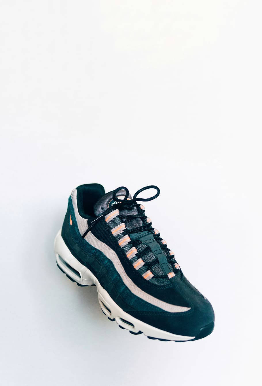 Nike Shoes 桌布 壁紙 — 一雙時尚的黑色Nike Air Max 95運動鞋，帶有蜜桃色點綴和白色鞋底，孤立在潔淨的白色背景上。