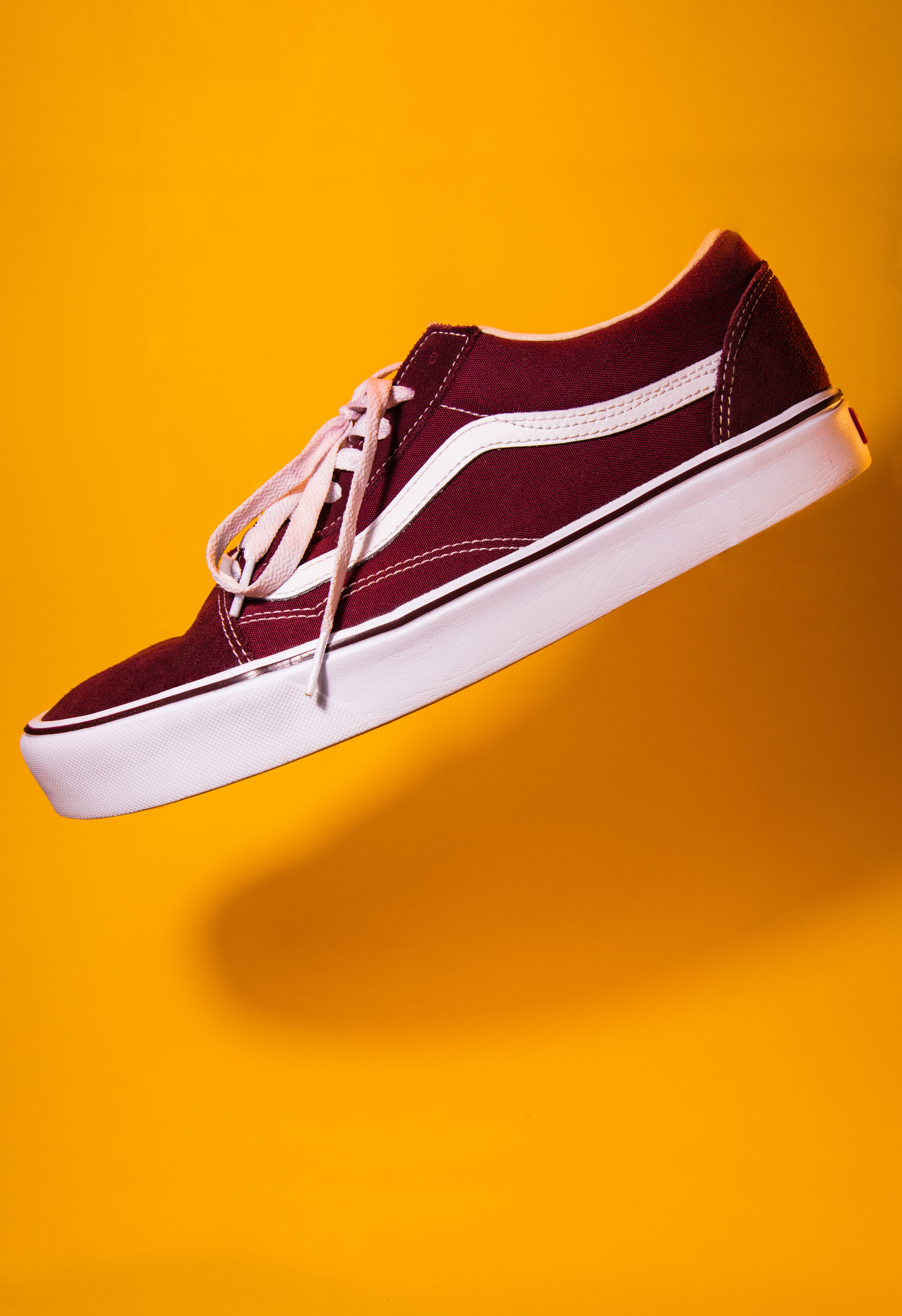 Vans 桌布 壁紙 — 一雙栗色Vans運動鞋，白色鞋底和鞋帶，在鮮黃色背景上漂浮。