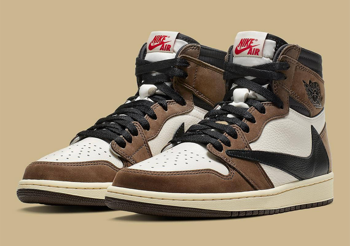 崔維斯·史考特 桌布 壁紙 — 一雙棕色、白色和黑色的Nike Air Jordan 1高筒鞋，帶有紅色品牌標誌，背景為米色。